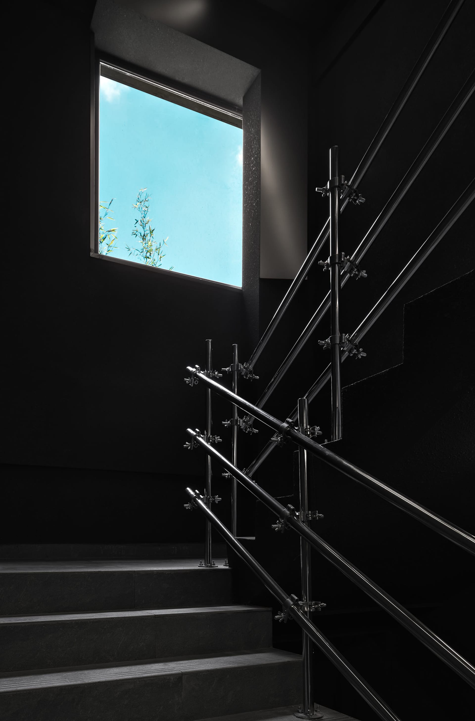 Dark interior staircase with metal railings in a black building with no natural light