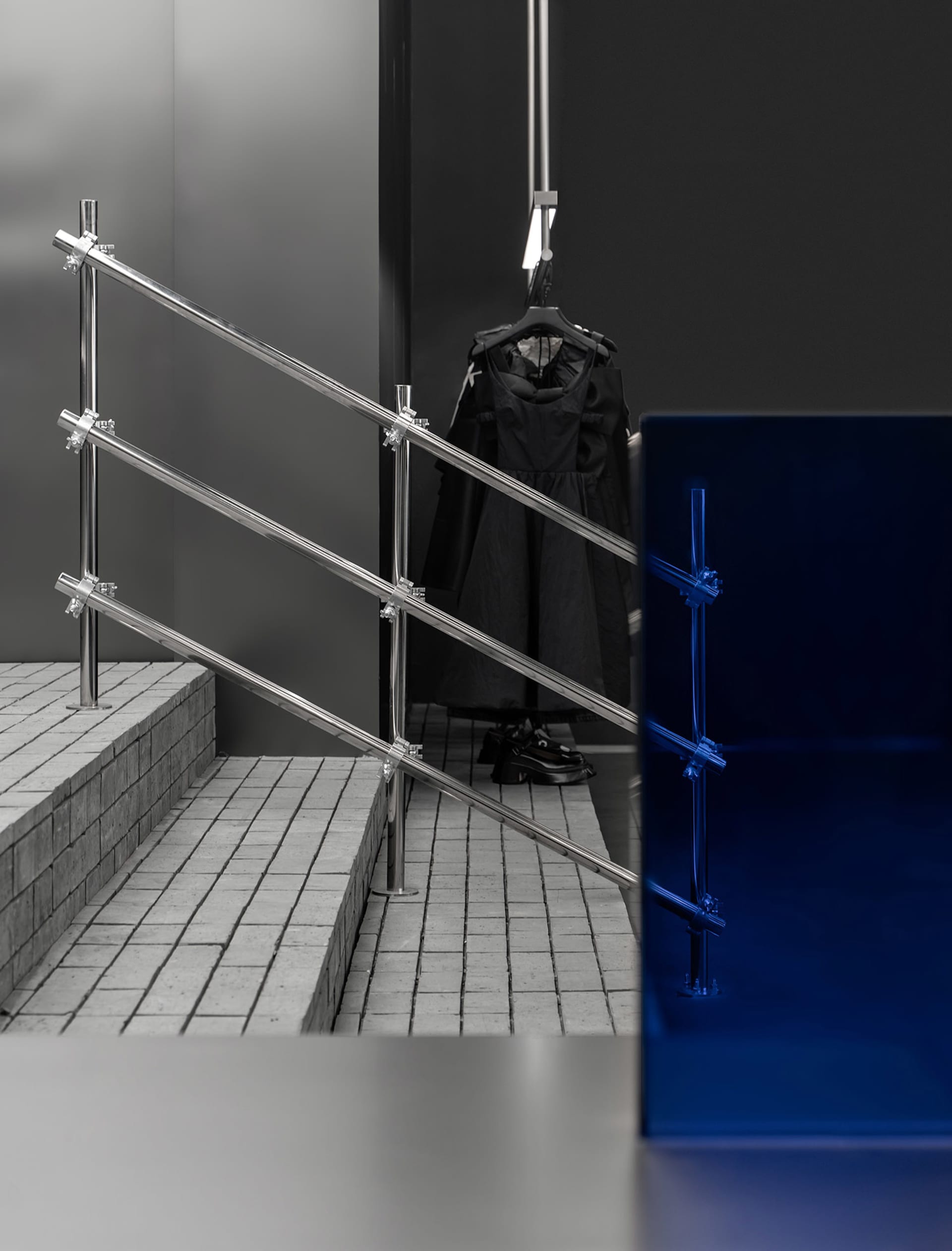 A black and white staircase with metal railings and two coats hanging on the railings, set against a neutral background