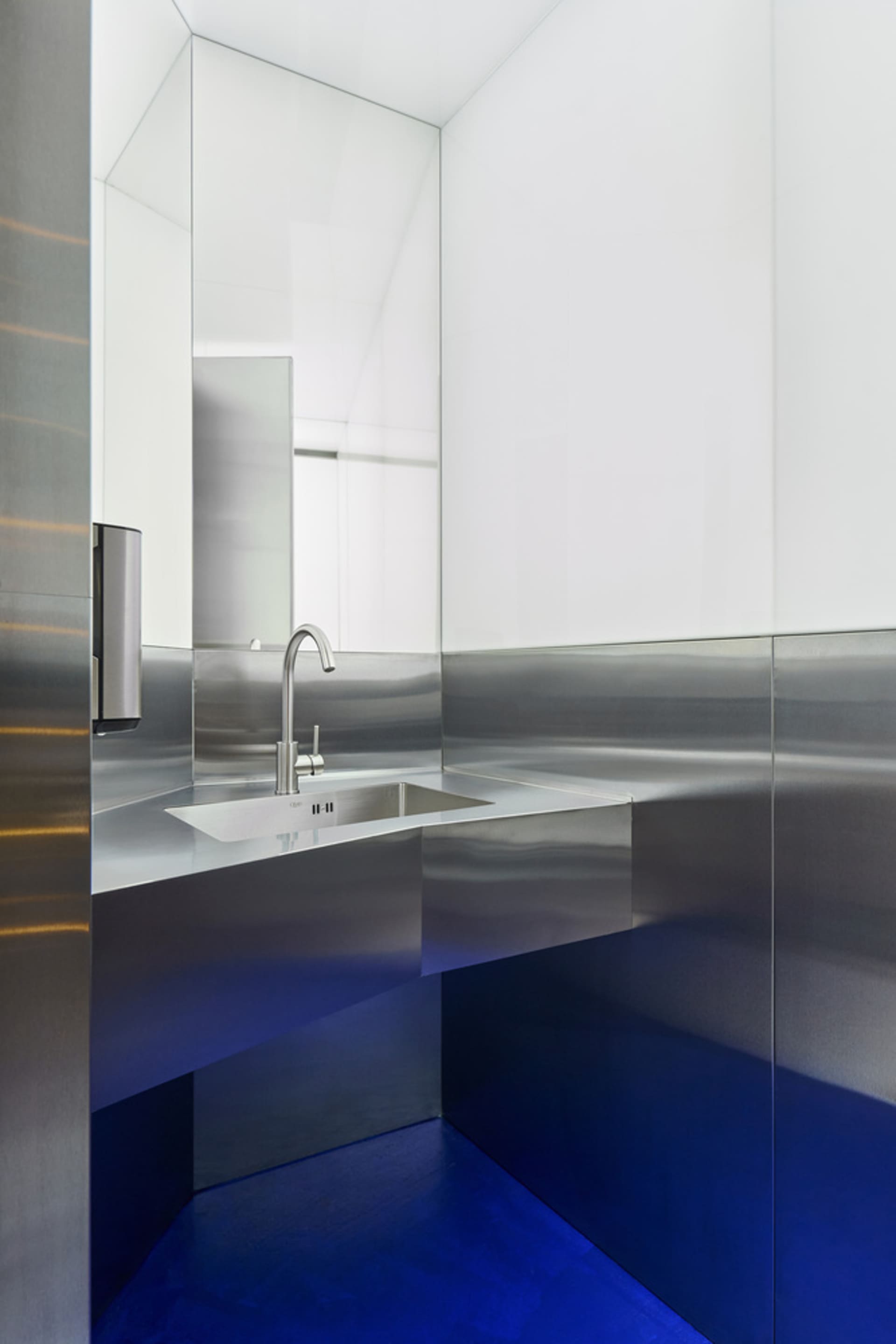 Industrial bathroom with a metal sink and mirror, featuring a silver-framed mirror and a well-lit atmosphere