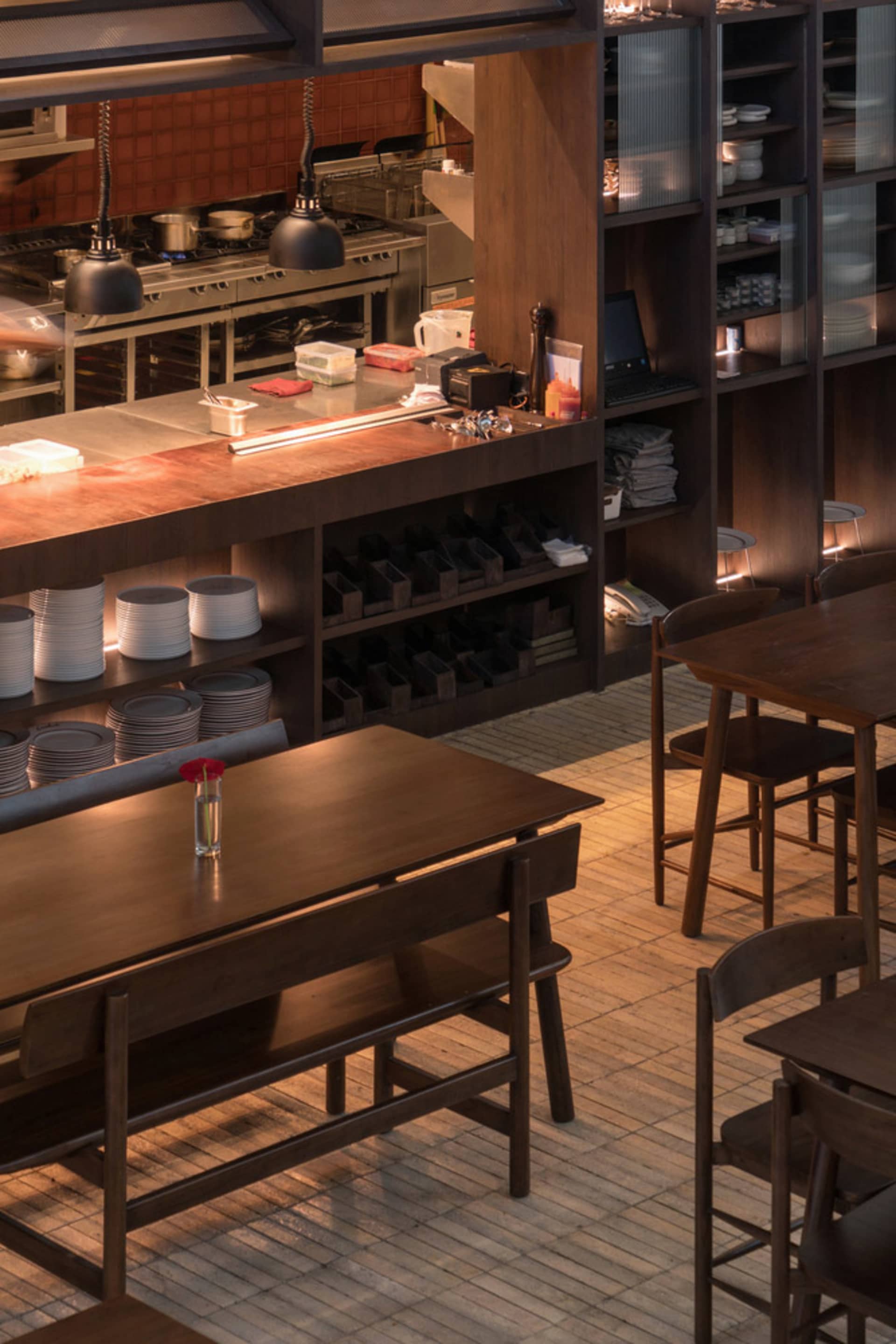 Warm and inviting restaurant kitchen with wooden tables, wine bottles, and various decorative items