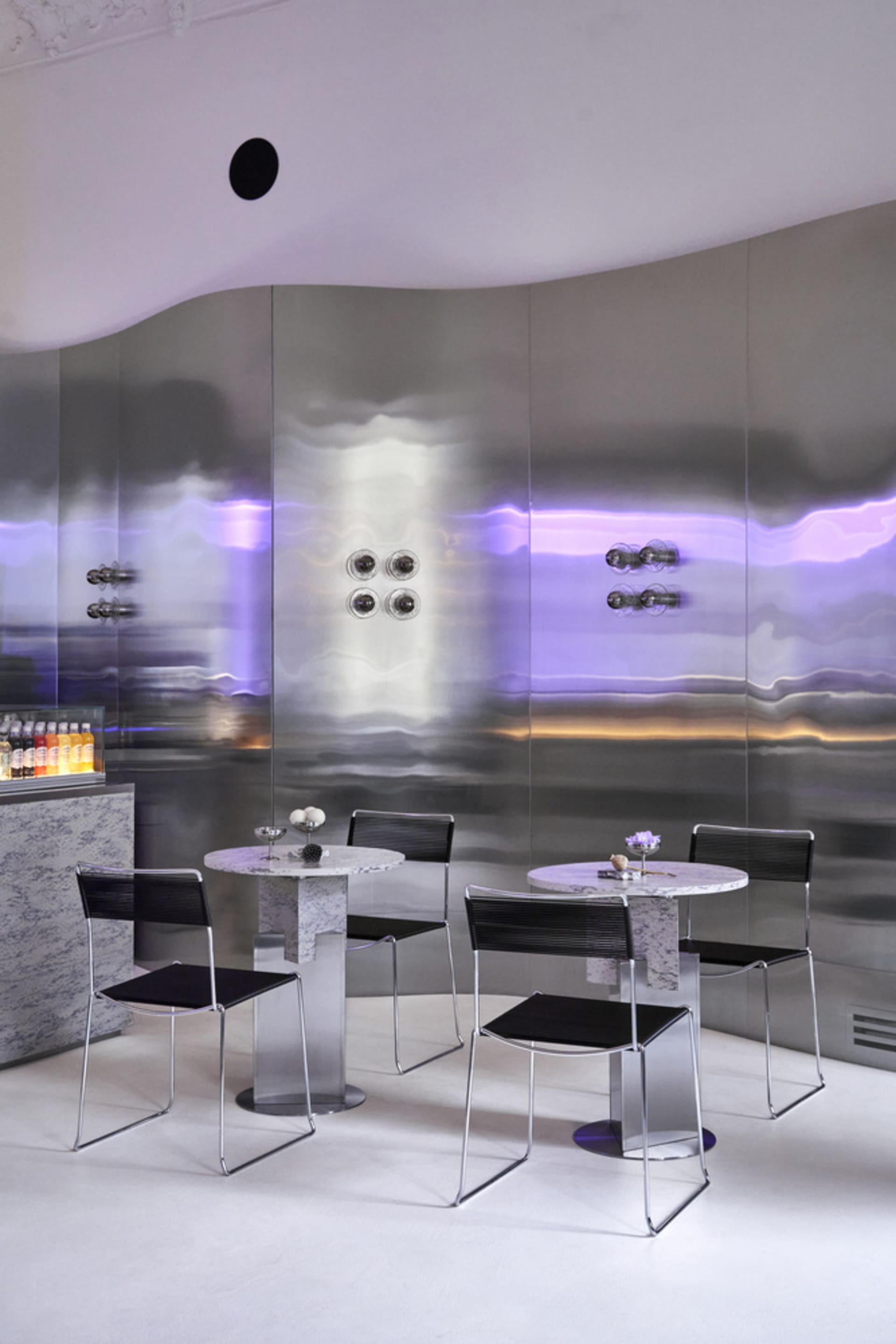 Modern bar area with a large mirror, tables, and chairs, providing ample seating and a stylish atmosphere
