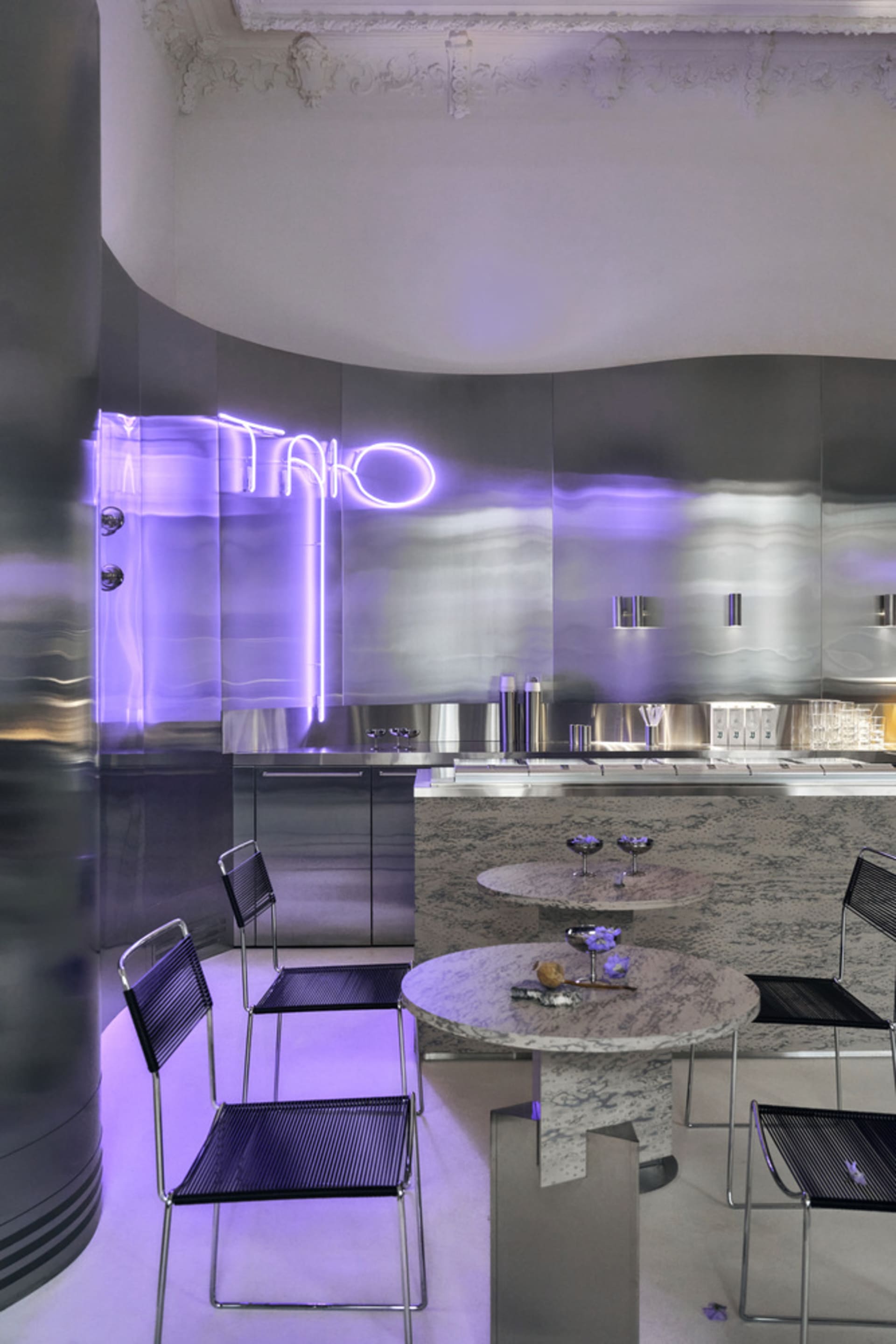 Modern restaurant interior with purple neon lights, sleek surfaces, dining area, kitchen, and contemporary design
