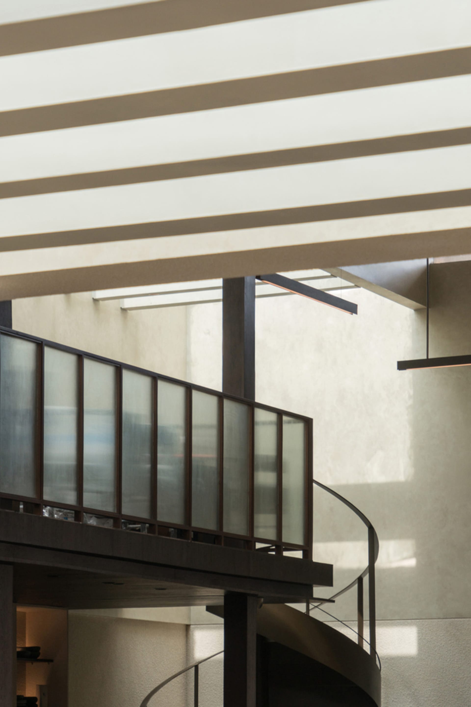 A spiral staircase made of wood in a white-walled stairwell, conveying a sense of openness and simplicity