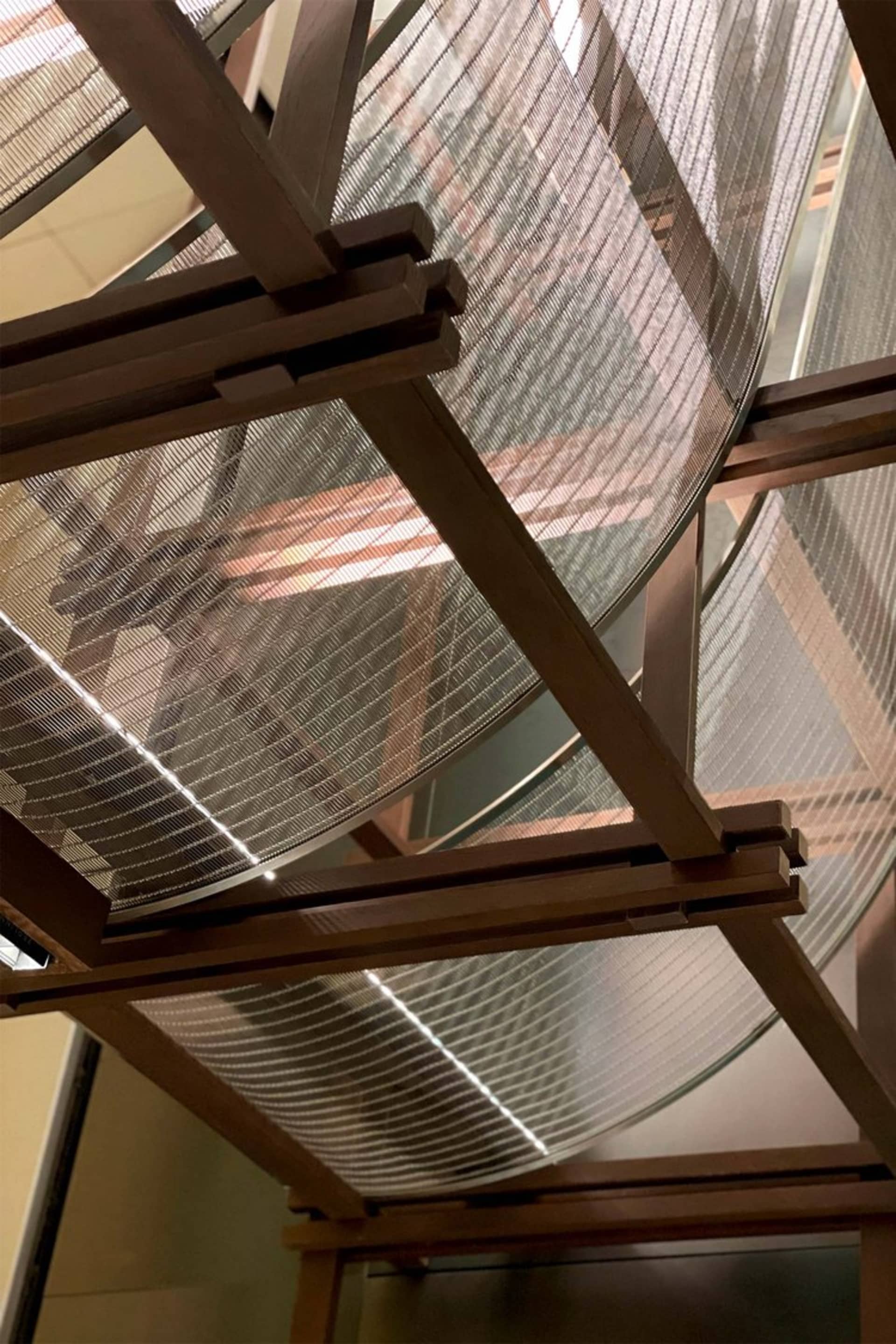 A modern staircase with a wooden and glass design, featuring a metal railing and natural light