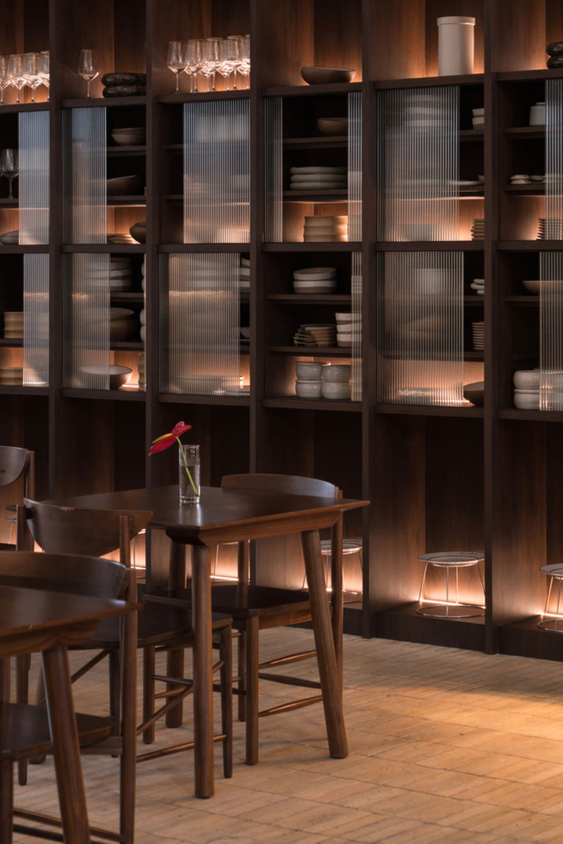 A restaurant interior with wooden floors and walls, featuring multiple dining tables, chairs, and wine glasses, creating a warm and inviting atmosphere