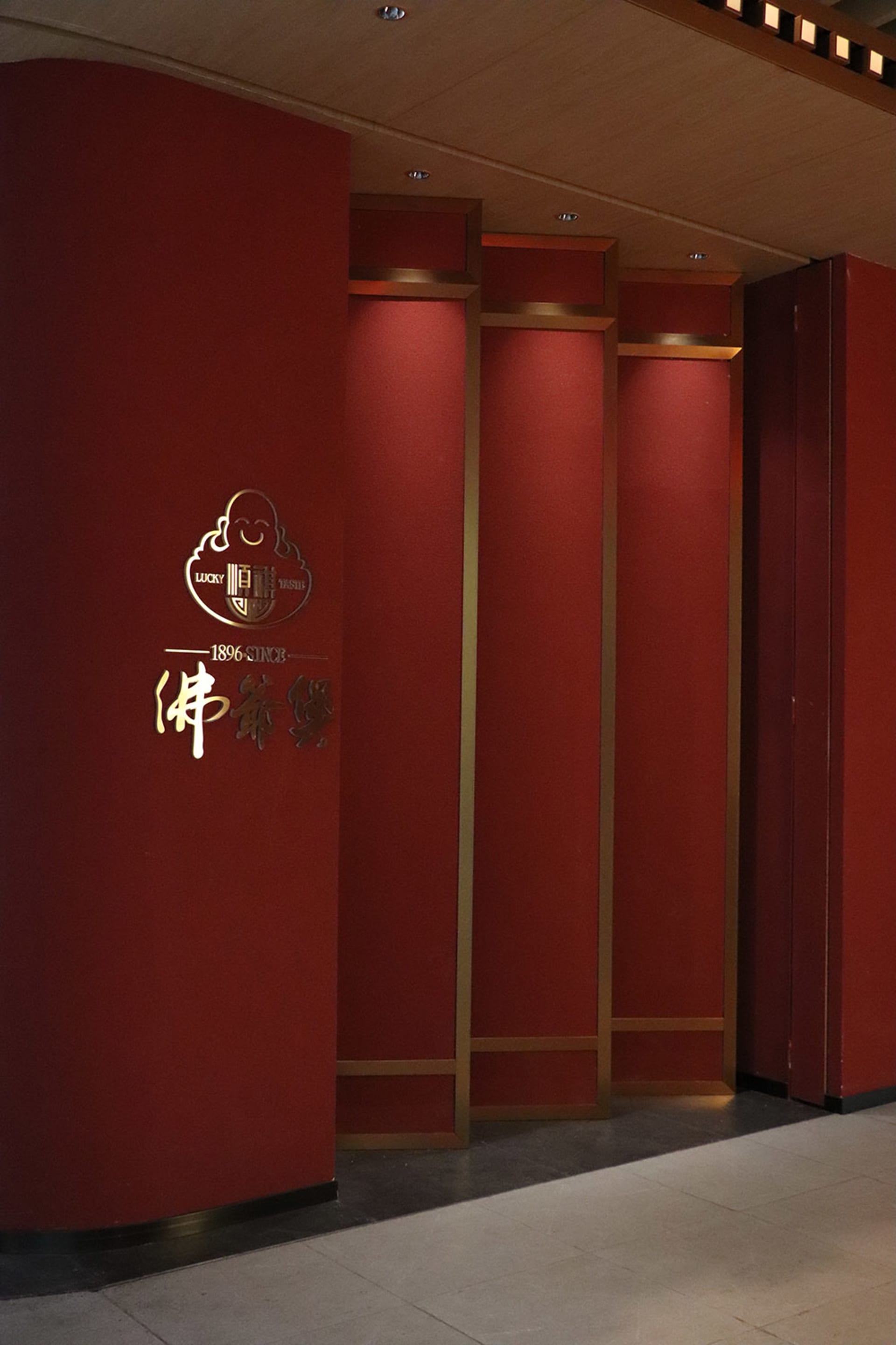 Ornate red wall with gold accents in a Chinese restaurant, featuring intricate designs, two doors, and a luxurious atmosphere