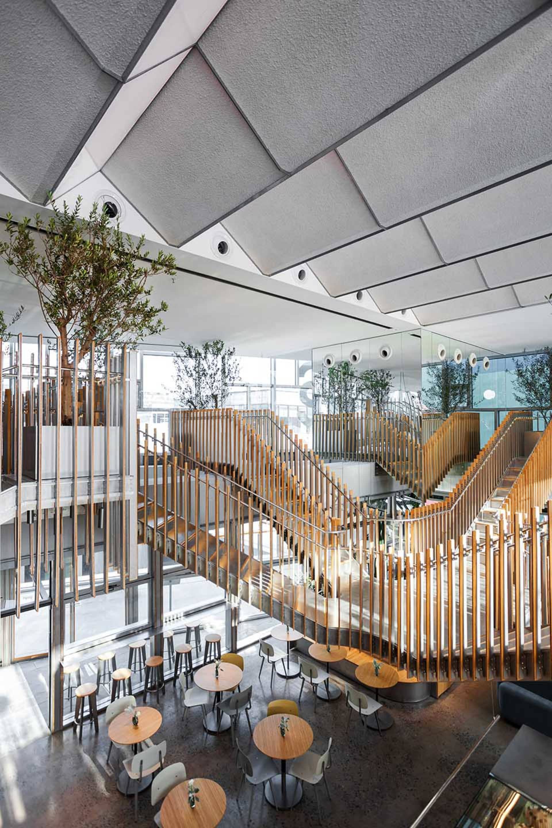 Dimly lit modern space with multiple levels, chairs, and dining tables, featuring clean lines and minimalistic decoration
