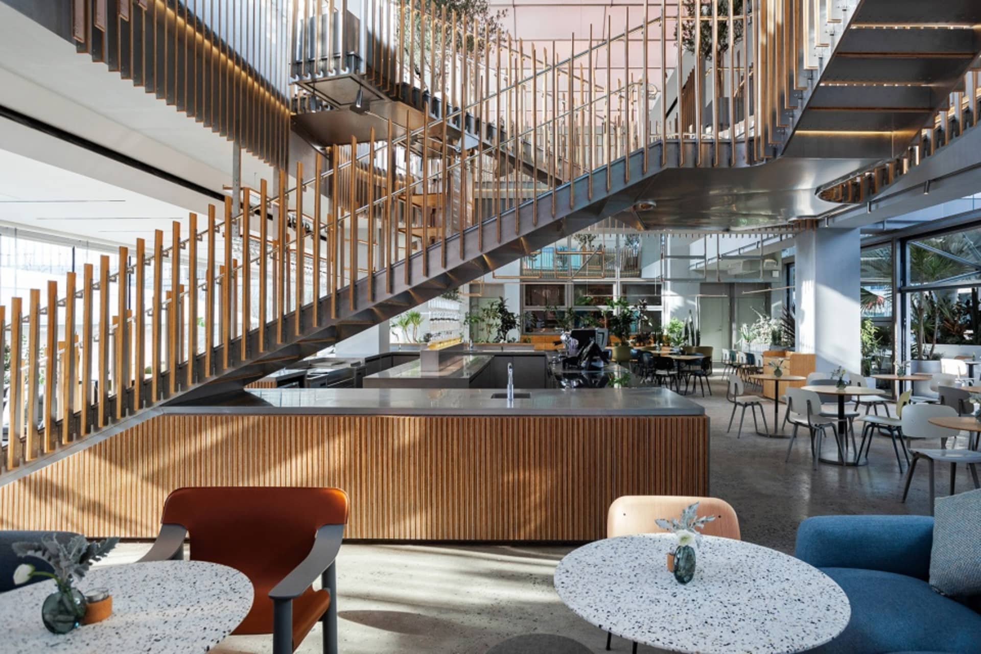 Open dining space with wood flooring, multiple tables, chairs, and potted plants, creating a modern and inviting atmosphere