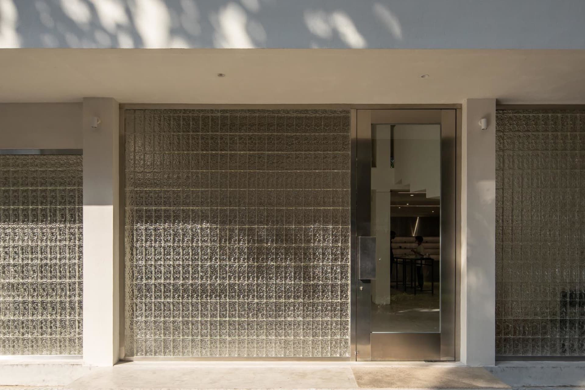 Modern entrance with a glass door featuring a pattern of squares, set within a metal frame