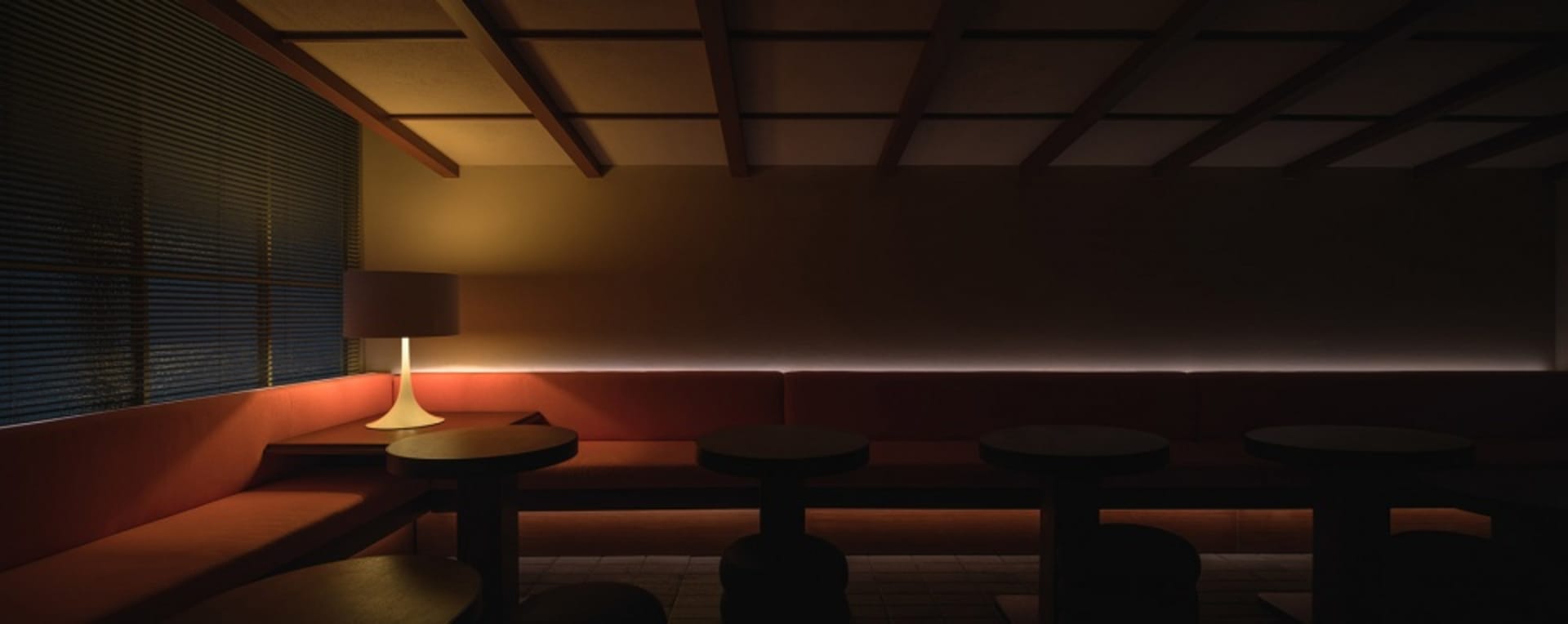 Inviting restaurant interior with a long bench seating area, multiple tables, chairs, and a couch, creating a cozy atmosphere for dining and socializing