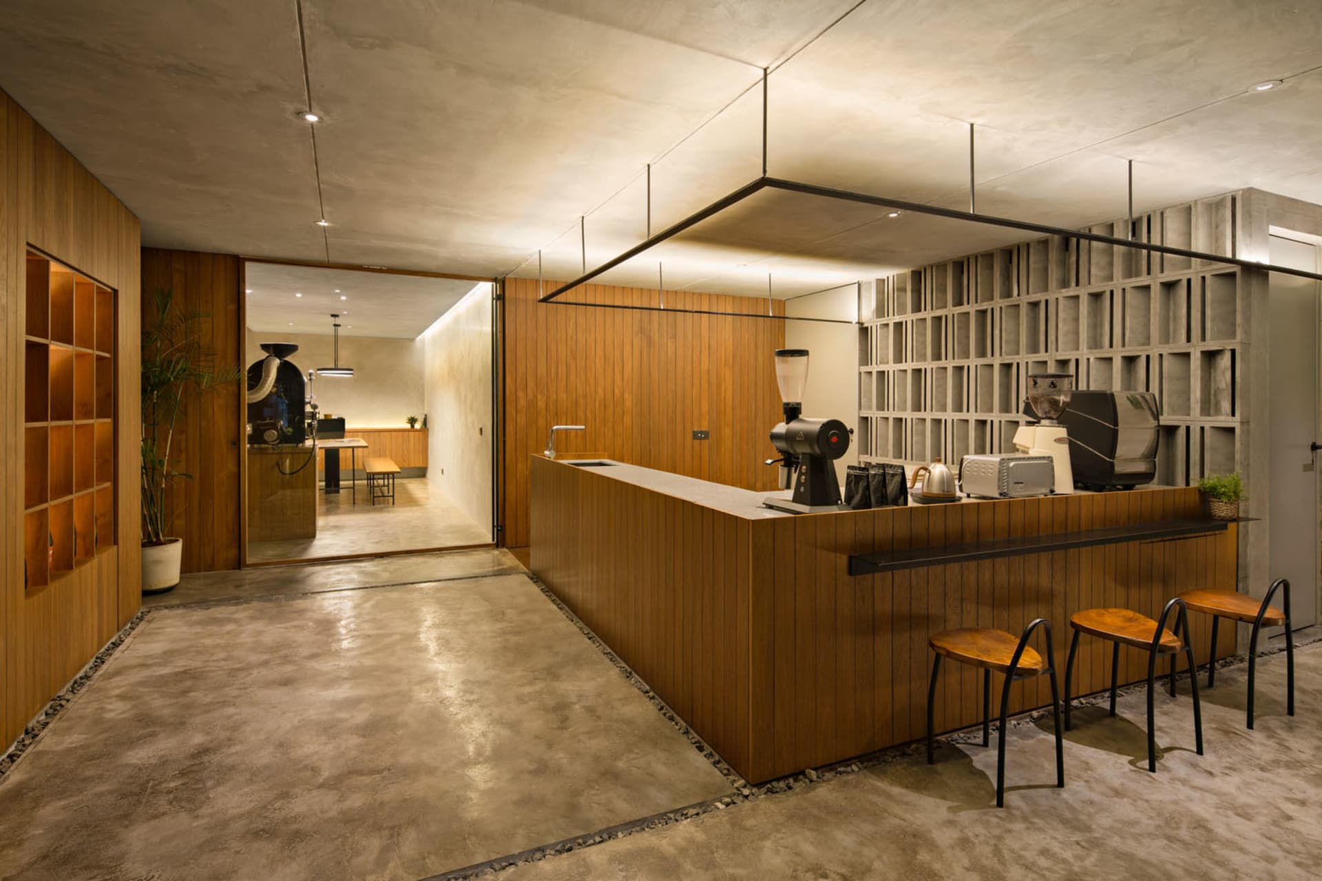 A cozy coffee shop interior with a counter, chairs, and a dining table, featuring a mix of wood and modern design elements