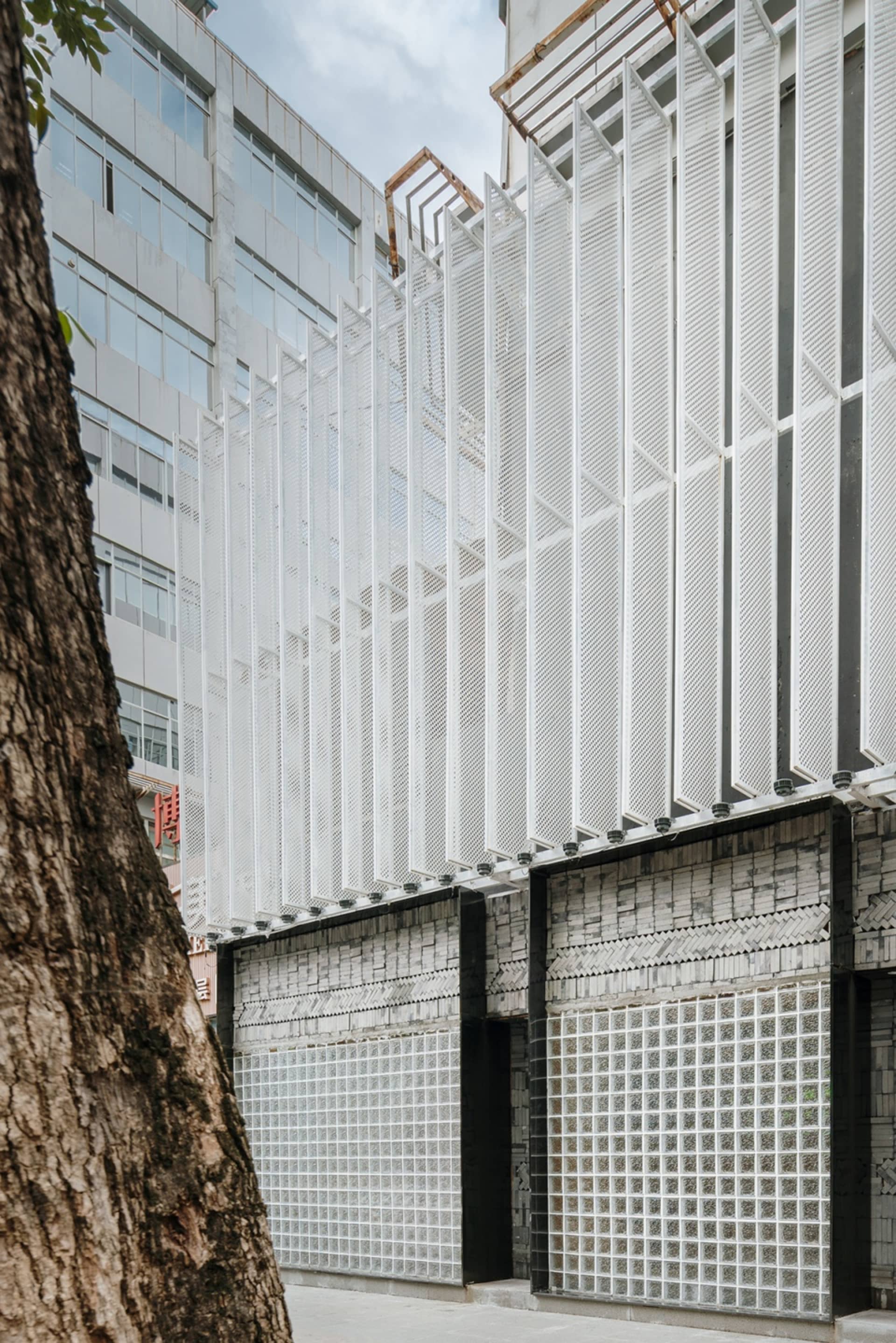 A modern building with a large glass wall and metal-clad exterior, featuring a minimalist and contemporary design with abundant natural light