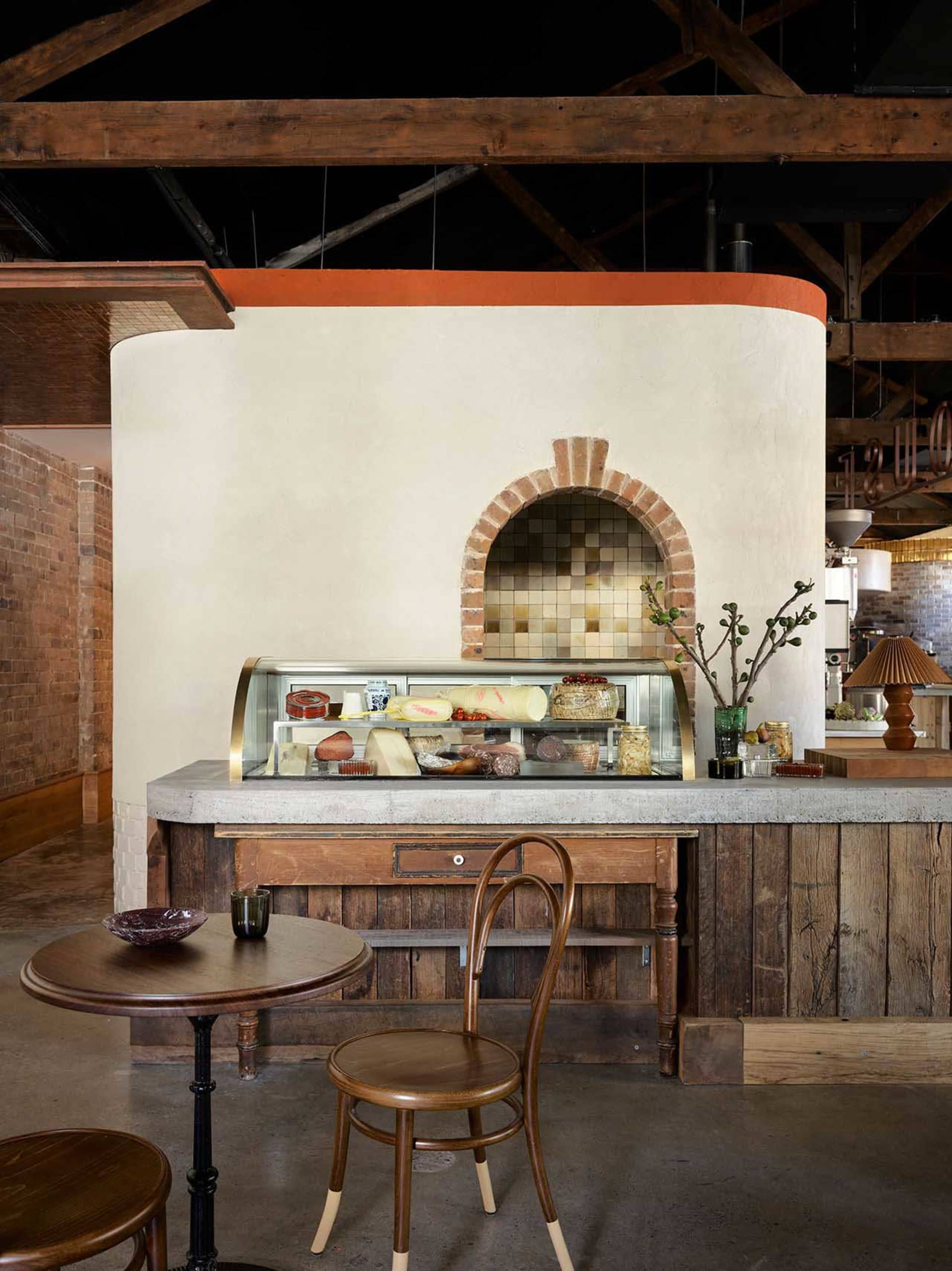 Warm and inviting cafe interior with a wooden counter, display case, and dining table, featuring a cozy atmosphere and natural materials