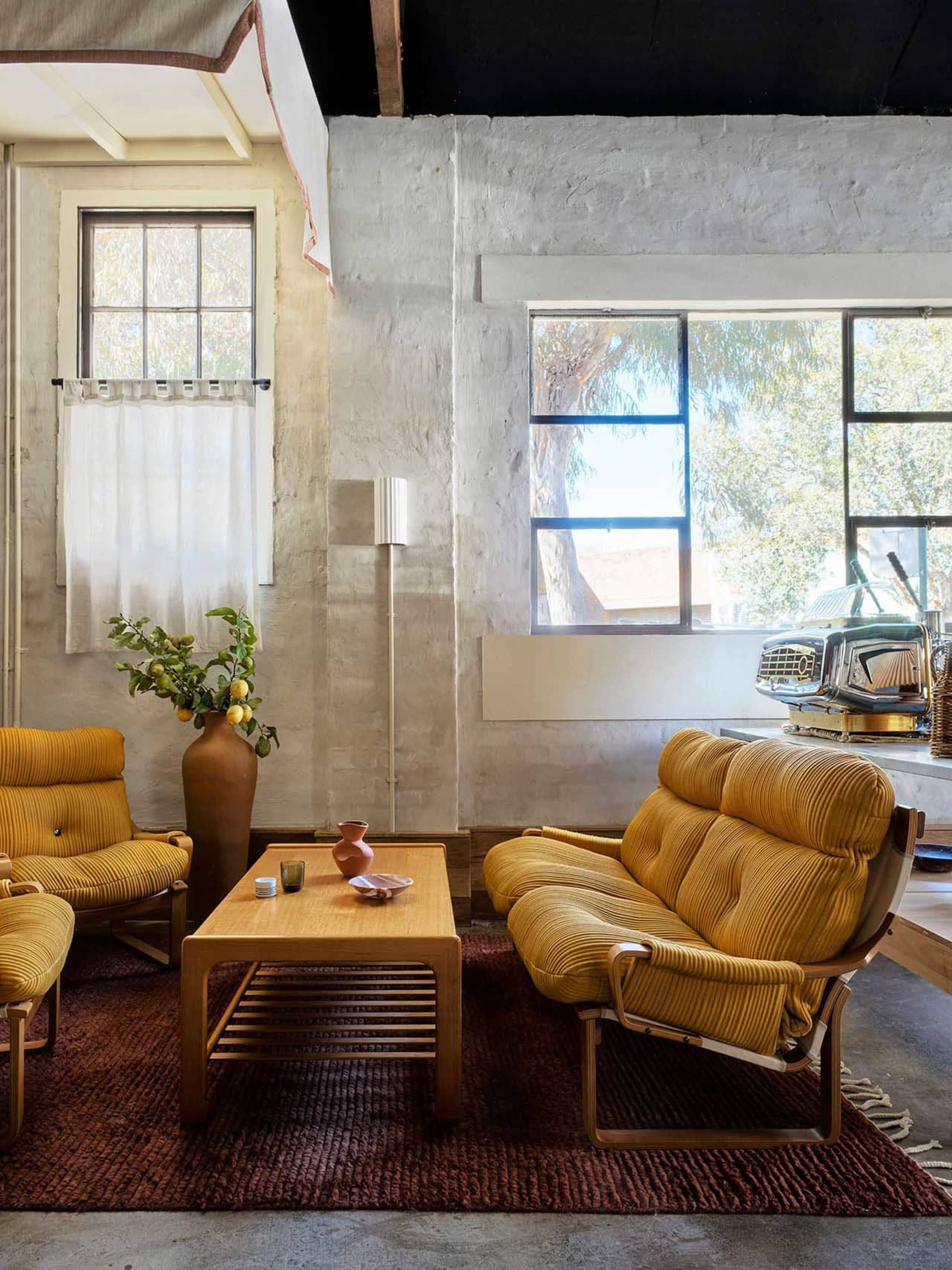 Cozy modern living room with yellow couches and chairs, a rug, and a coffee table, featuring a welcoming atmosphere and natural lighting