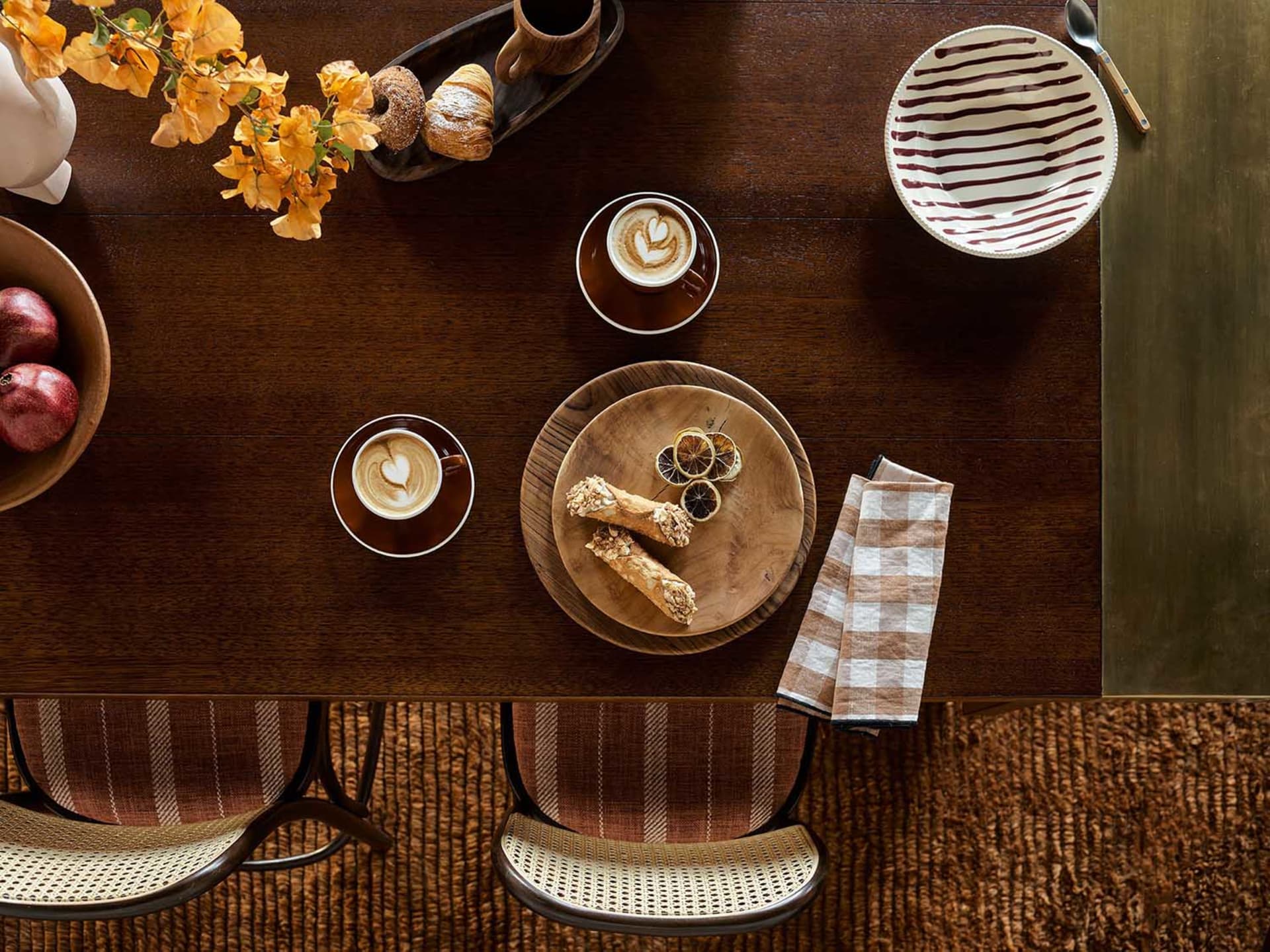 A wooden table set with coffee cups, pastries, and cakes in a warm and inviting atmosphere