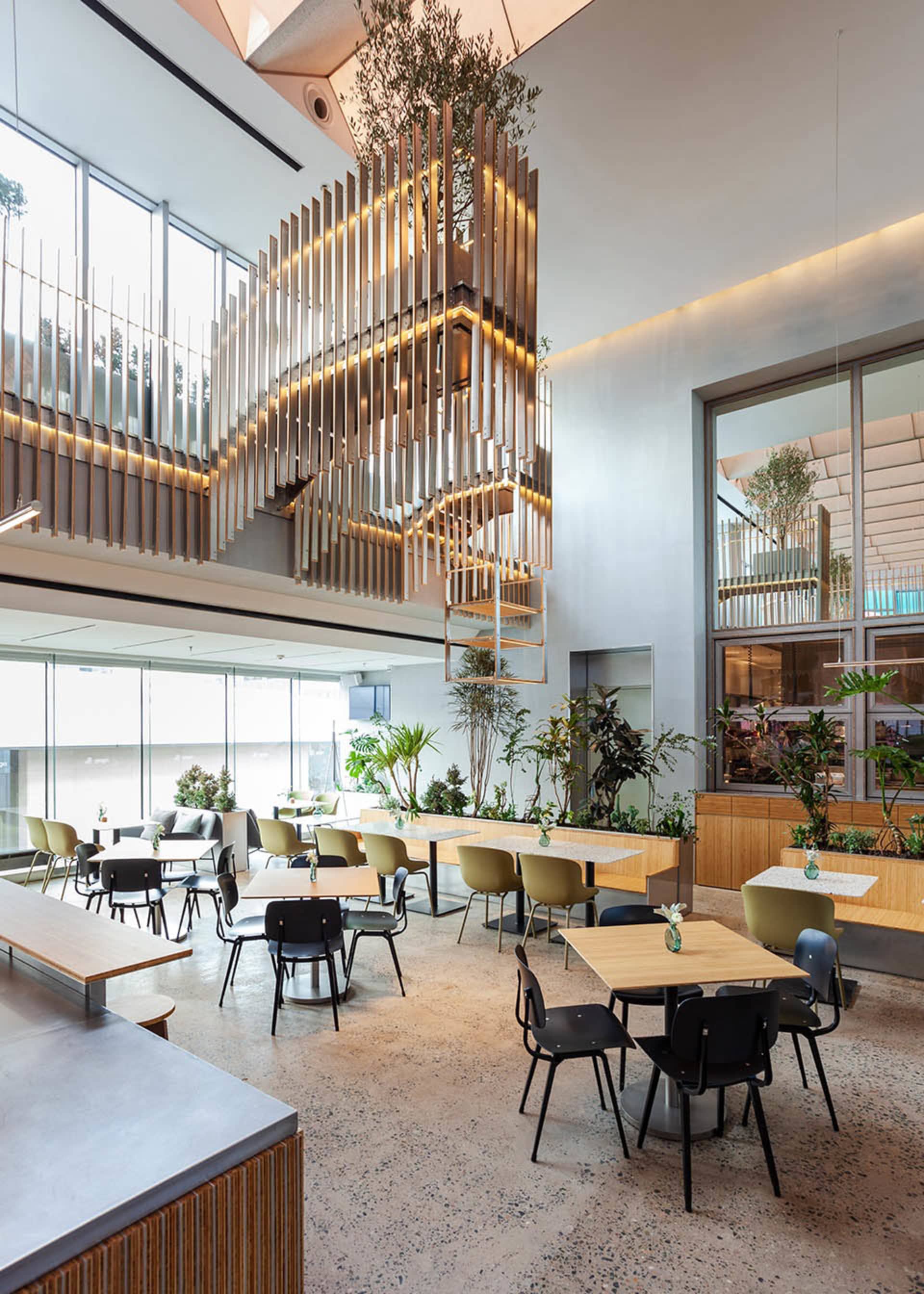 Open modern restaurant interior with wooden floors, tables, and chairs, featuring a bar and comfortable seating for guests