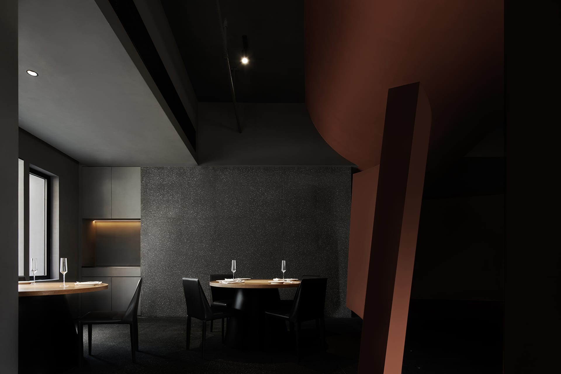 Dark dining space with a large table, wine glasses, and a sophisticated ambiance