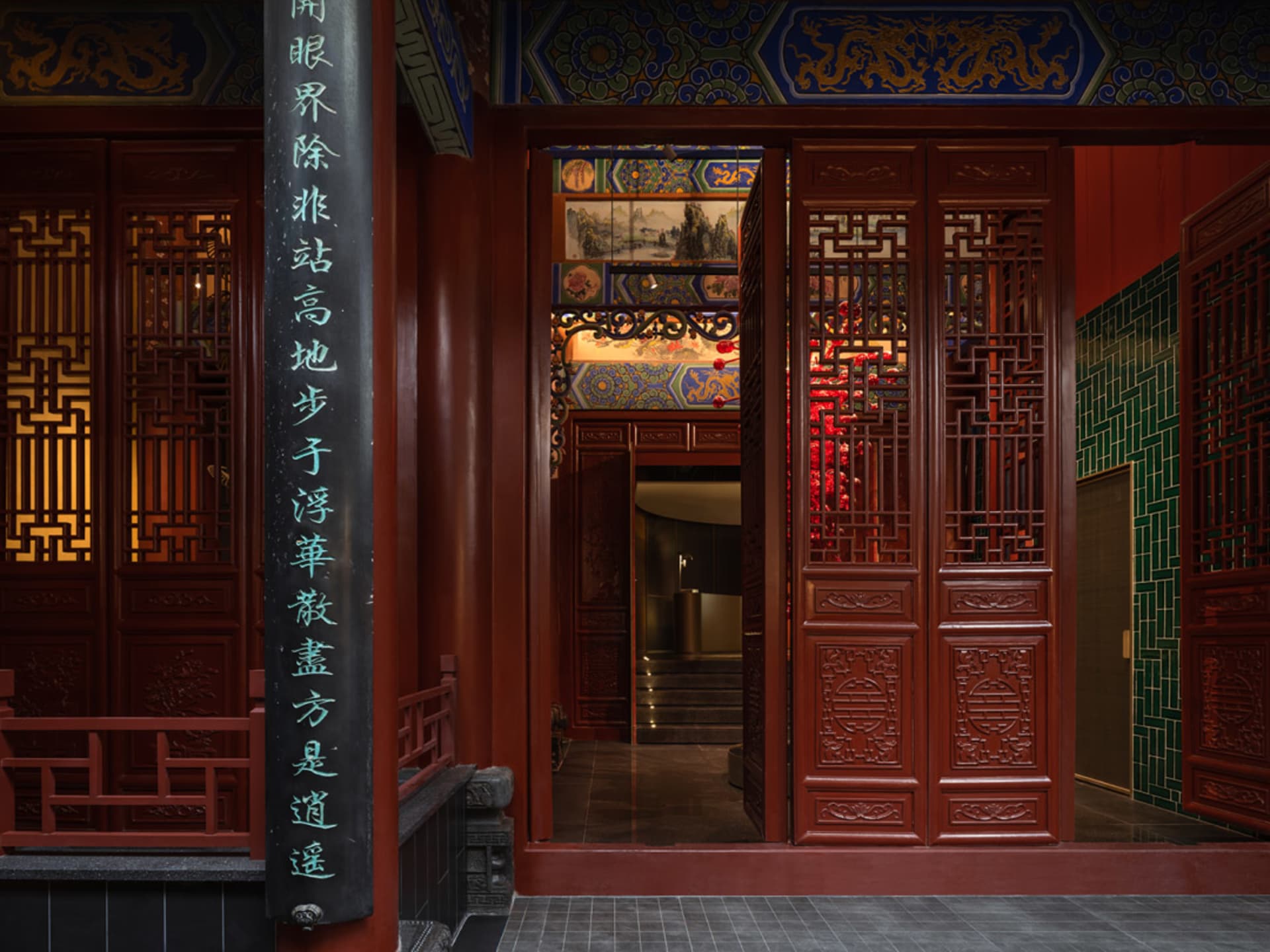 Ornate red building with Chinese lettering and intricate carvings, featuring a large archway entrance and comfortable seating areas