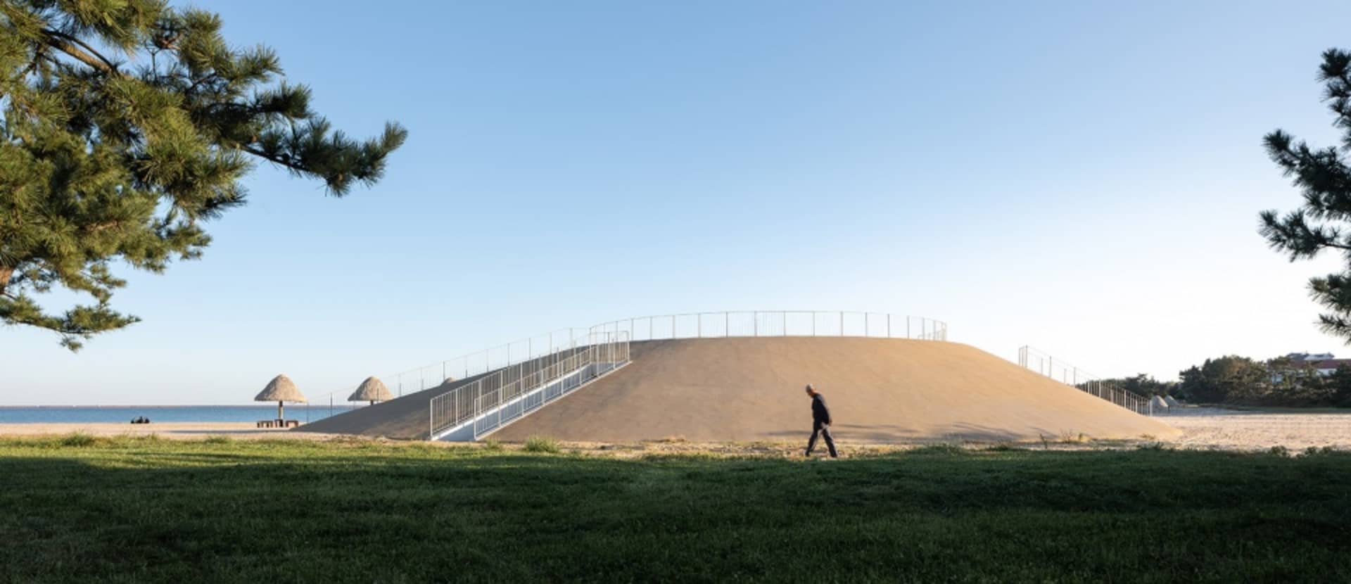 A large building with a concrete structure and metal fence, with two people walking in the area, creating a calm and peaceful atmosphere