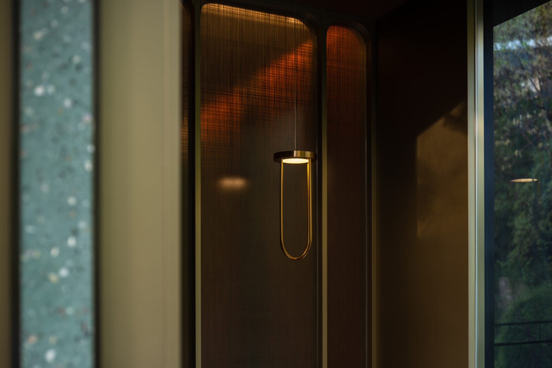 A warm and inviting entryway with a wooden door, a gold light fixture, and brown tones