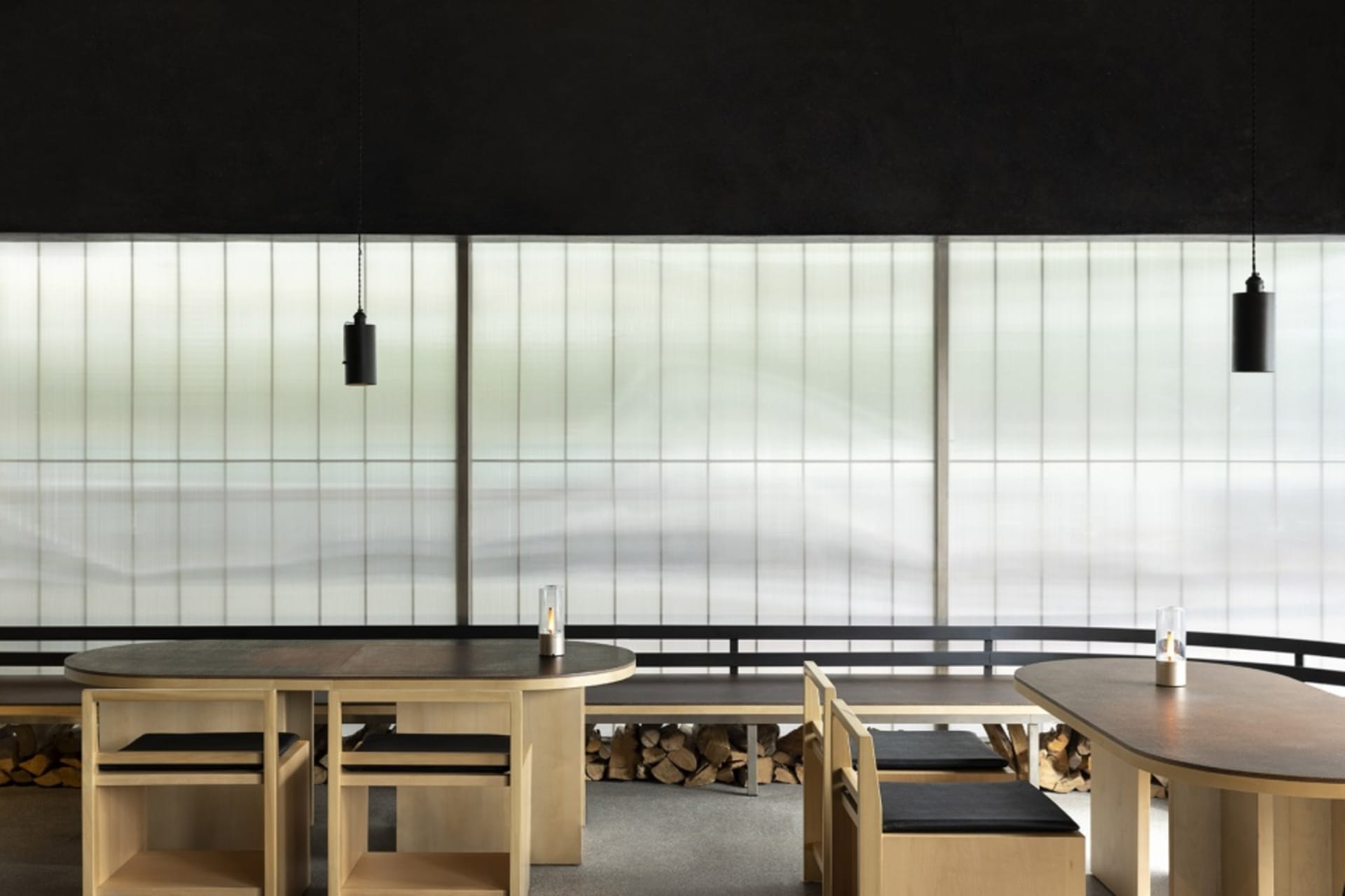 A modern cafe with wooden tables and chairs, black walls, and a cozy atmosphere