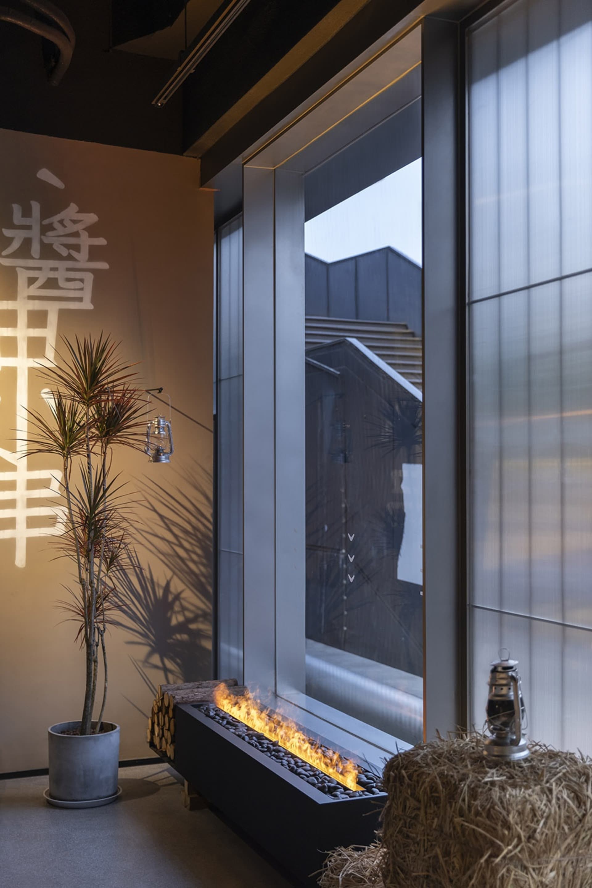 Warm and inviting living area with a fireplace, potted plants, and a vase, set against a neutral background