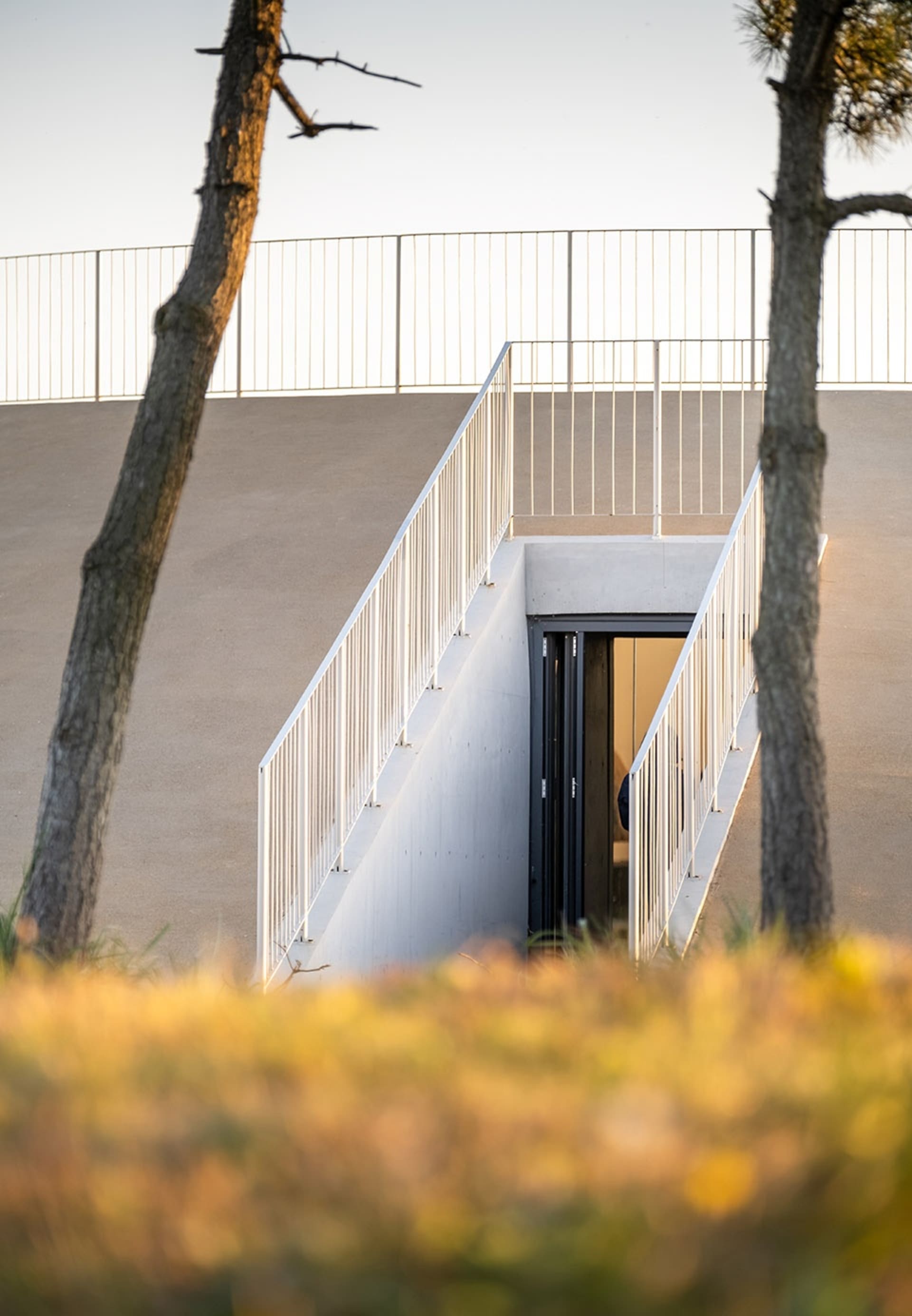 A modern building with a metal staircase leading to a doorway, with a person standing near the bottom of the stairs