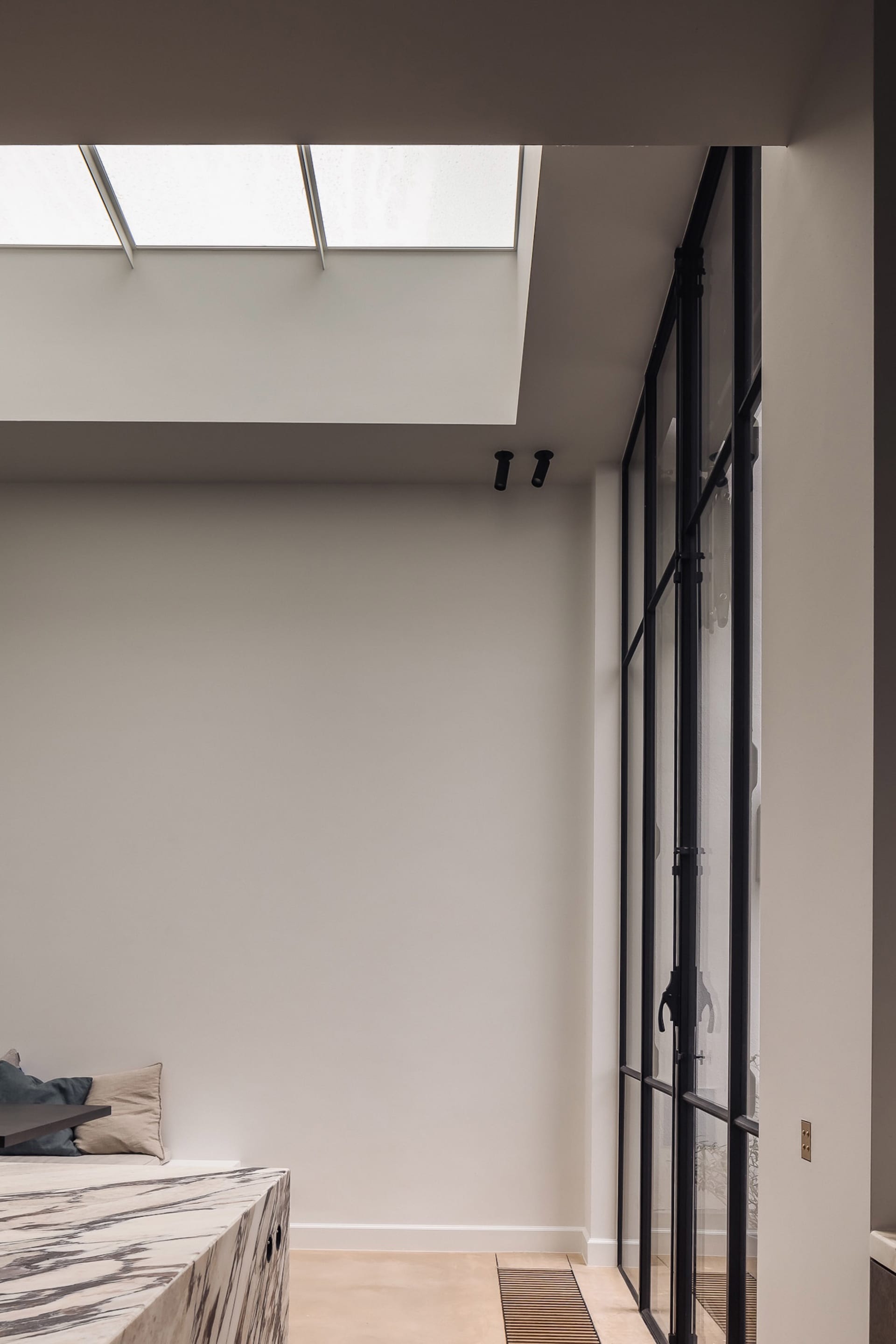 Empty living room with white walls and a large window, two couches, and natural light from the window