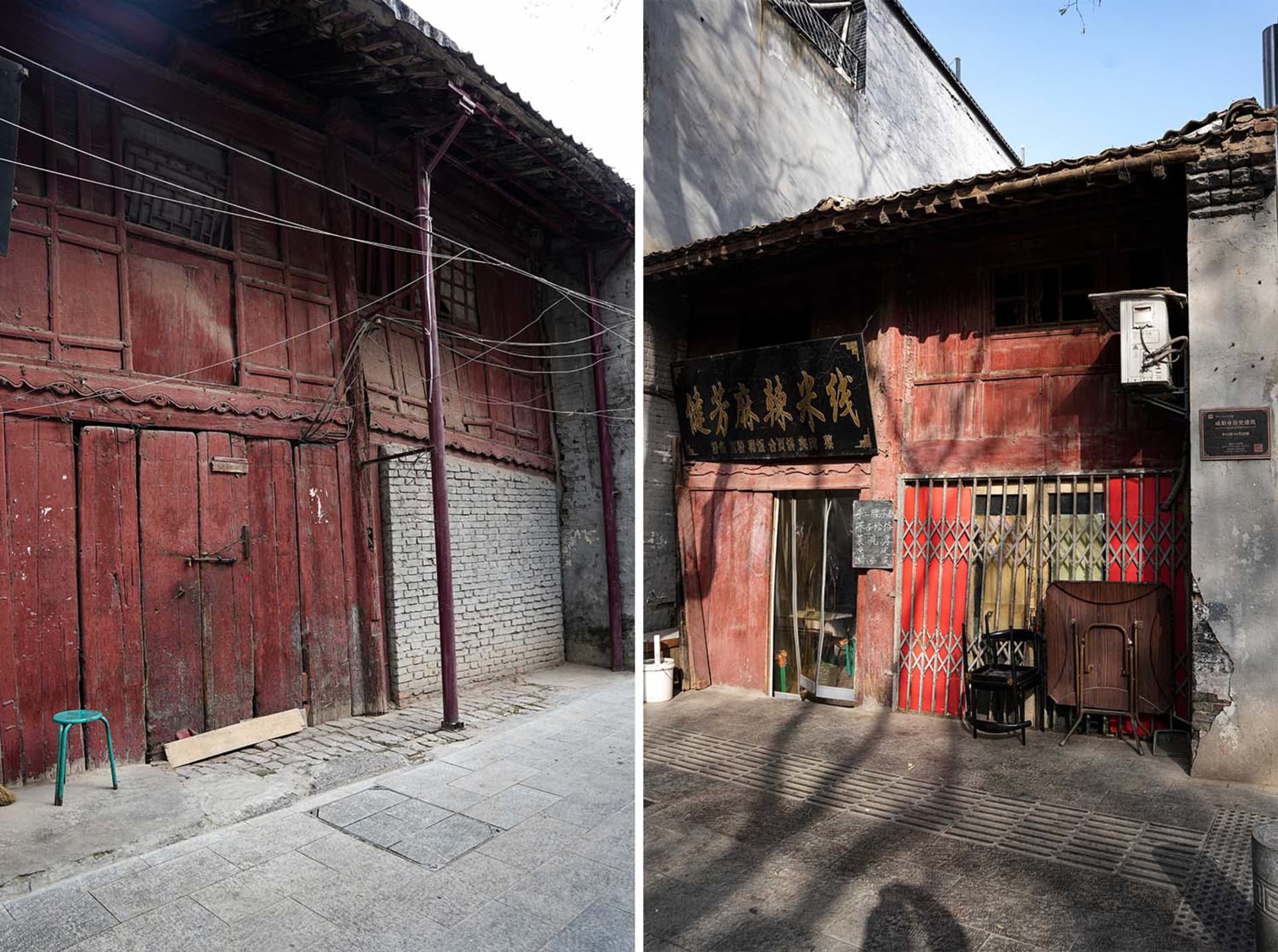 A worn old building with a brick exterior, red doors, and scattered chairs and benches in a outdoor setting