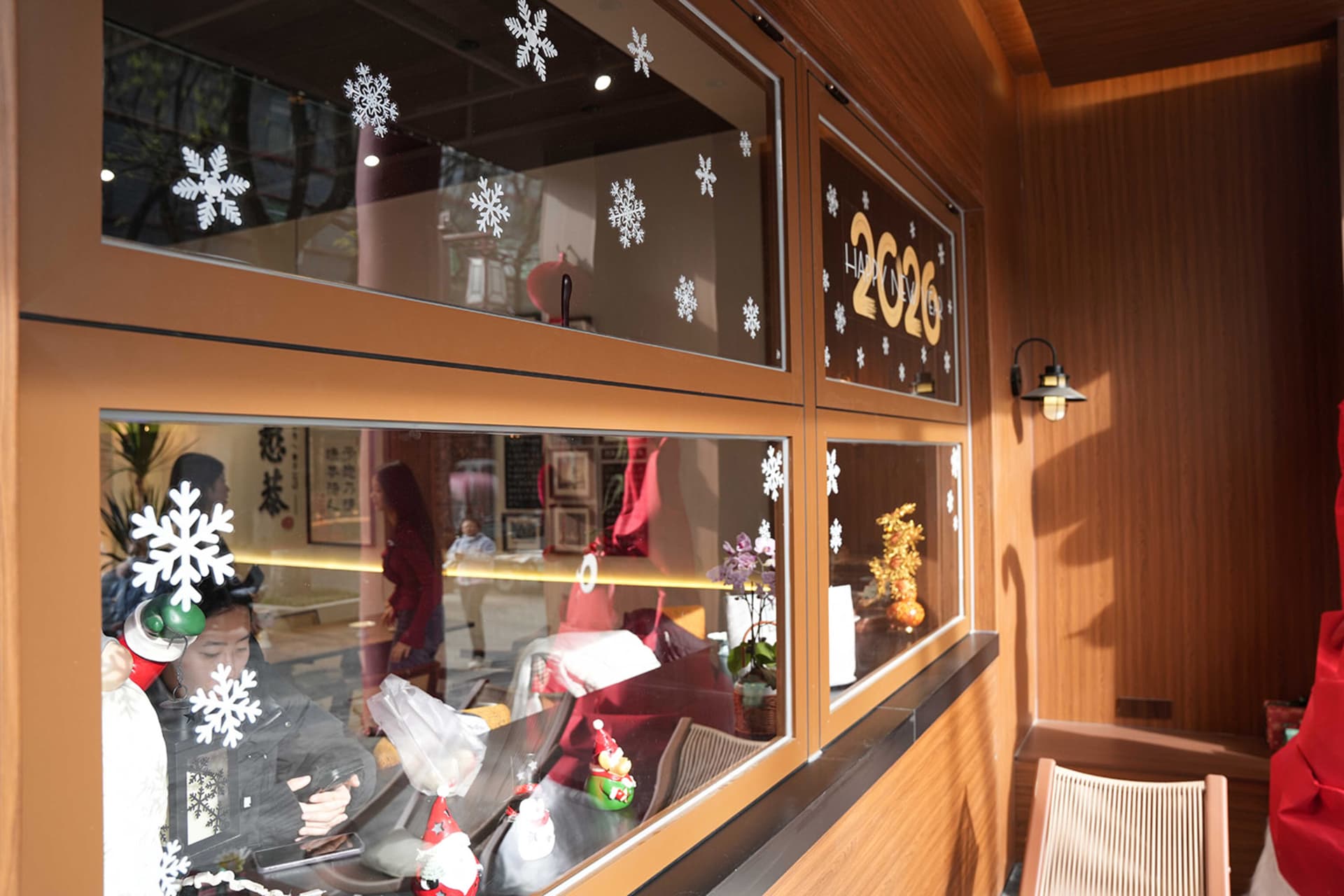 A retail storefront window display of winter clothing items with snowflakes on the glass, set against a background of people in a retail environment