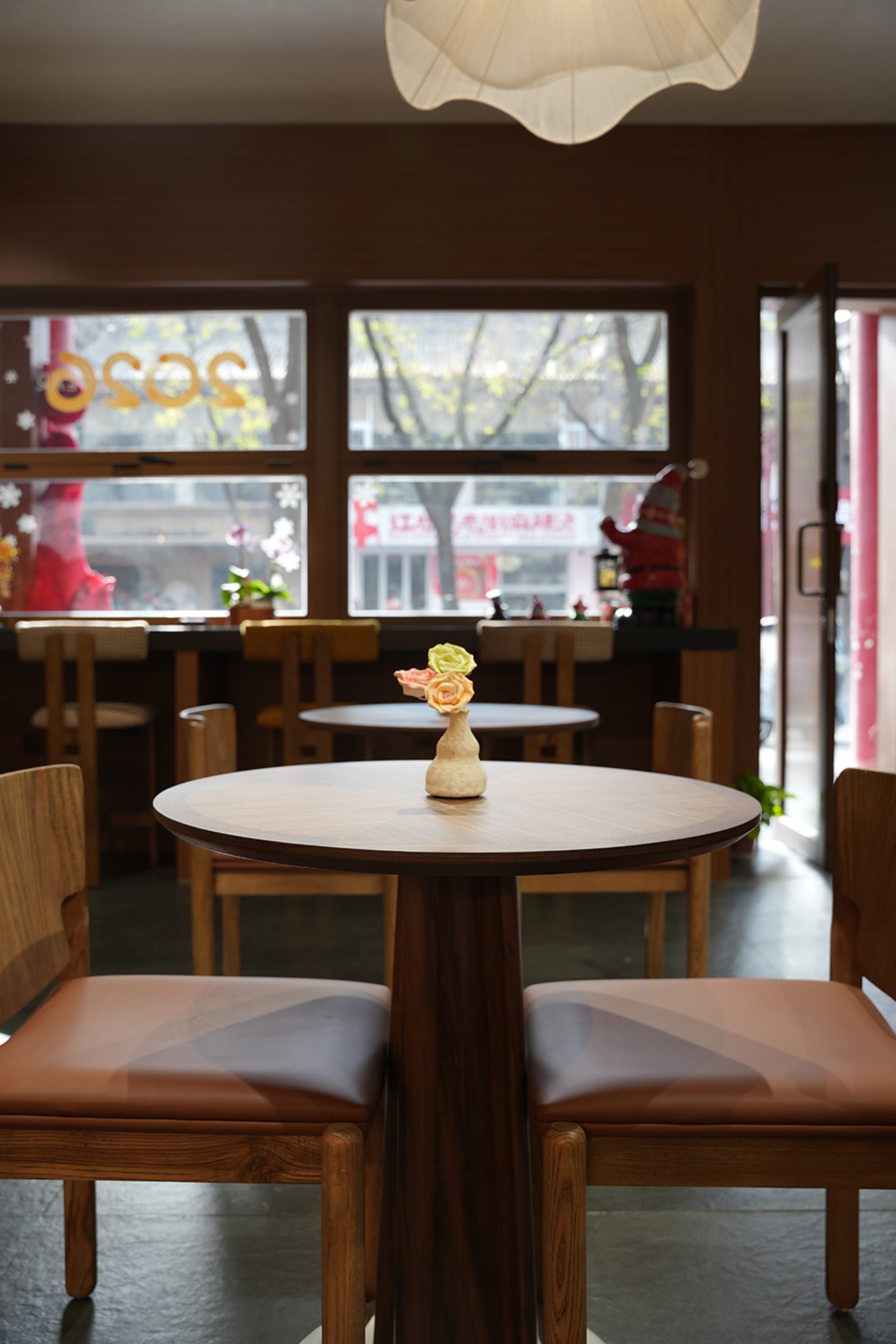 A cozy restaurant interior with wooden tables and chairs, a vase on one table, and an inviting atmosphere