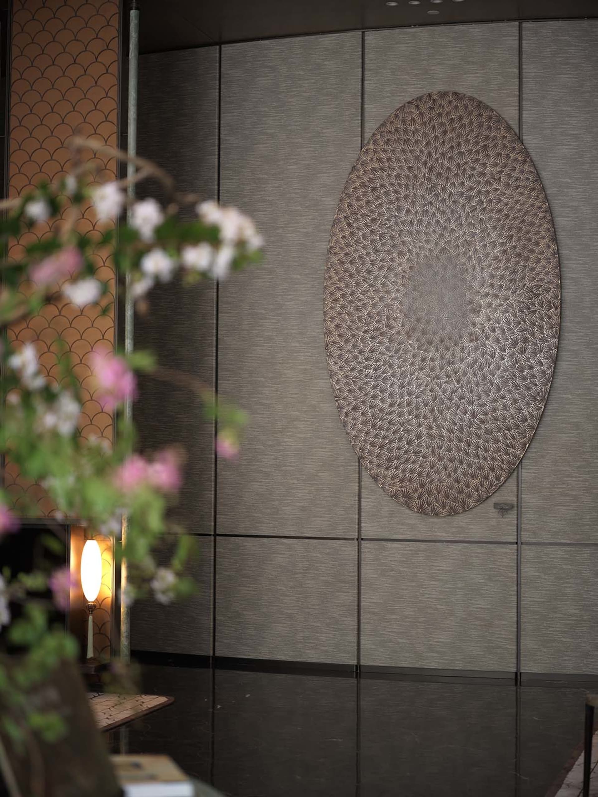 A sophisticated interior space featuring a large leather artwork mounted on a wall, surrounded by smaller decorative circles and elegant atmosphere