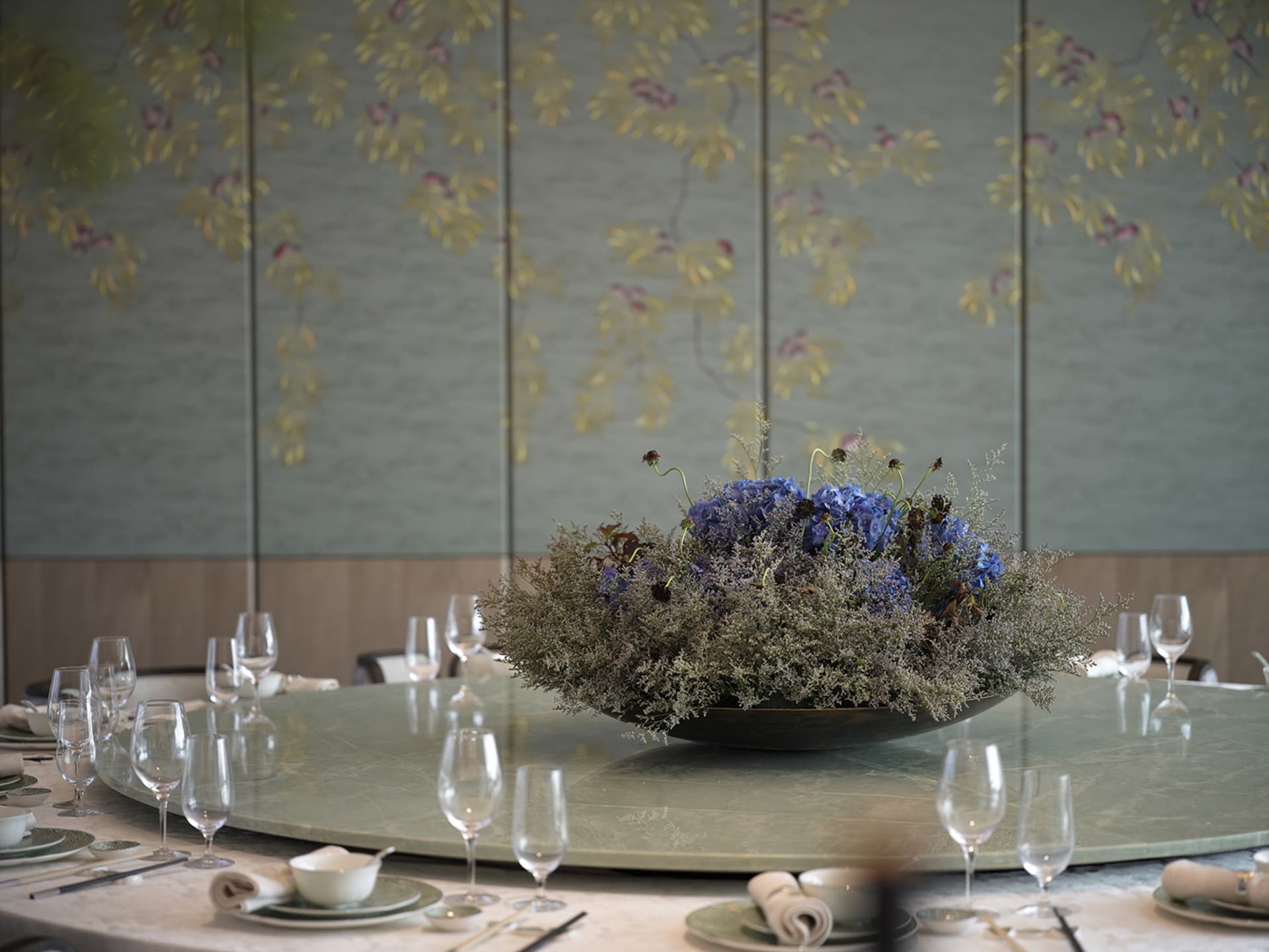 Elegant dining area with a round table, flowers, wine glasses, and fine china