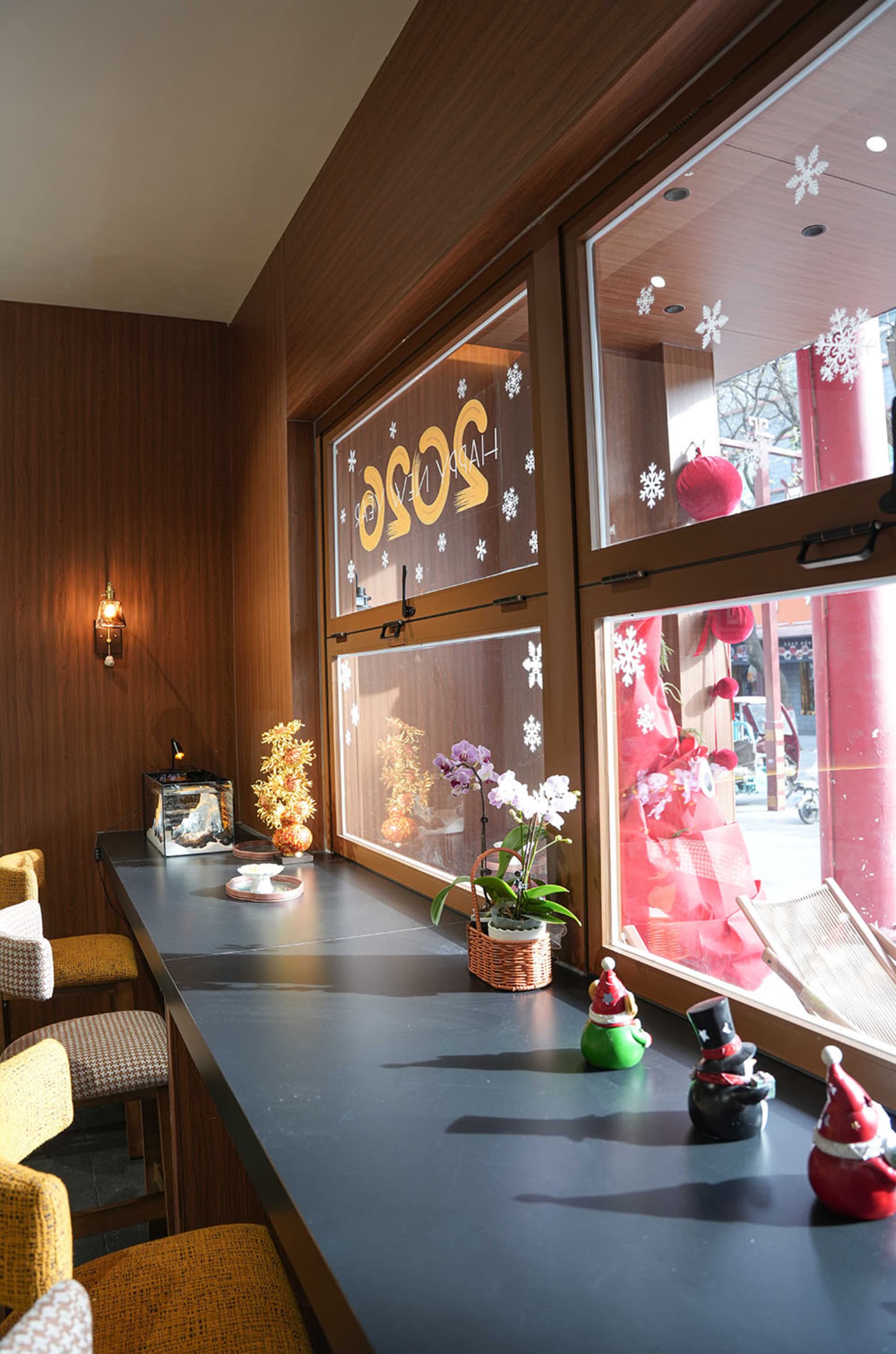 A well-lit dining area with a wooden table surrounded by chairs, featuring potted plants and various decorative items