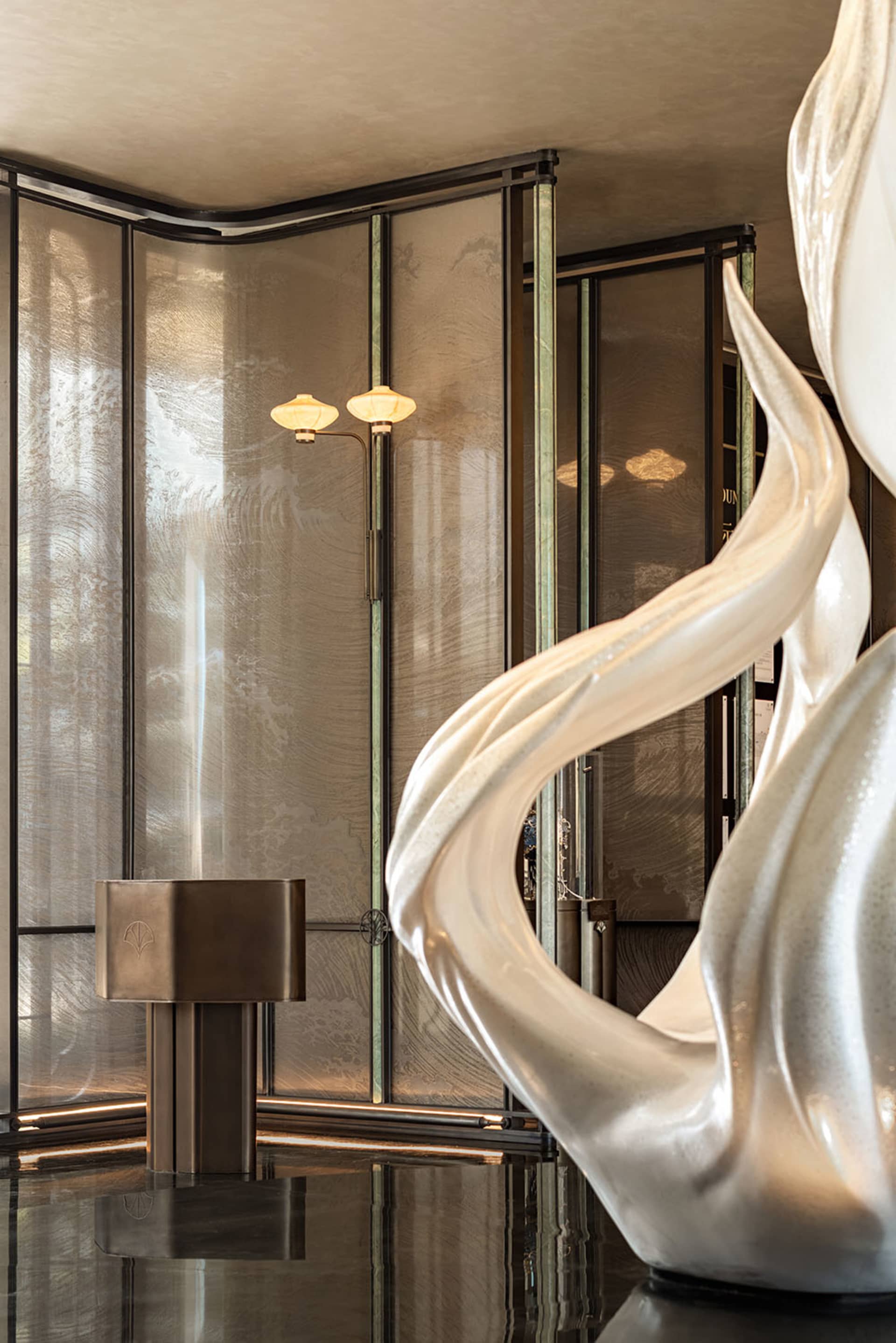 A modern interior space with a large marble sculpture, glass wall, and two lights, creating a contemporary atmosphere