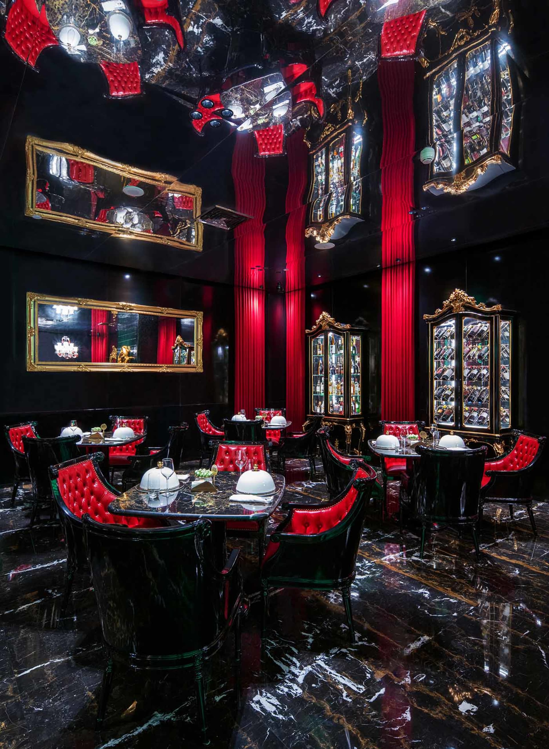 Elegant restaurant interior with red walls, black tables and chairs, and artwork on the walls