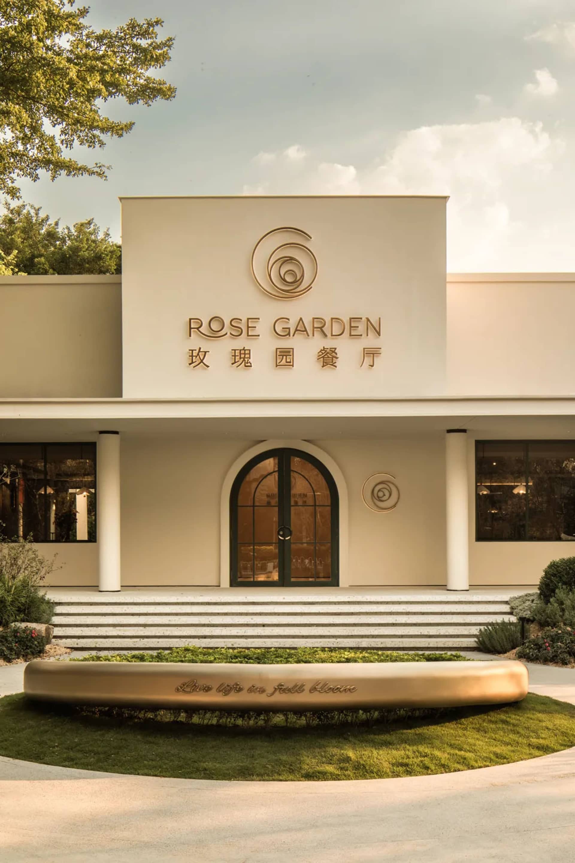 A white concrete building with a large circular window on its facade and two smaller round windows in front, possibly a garden center or similar establishment