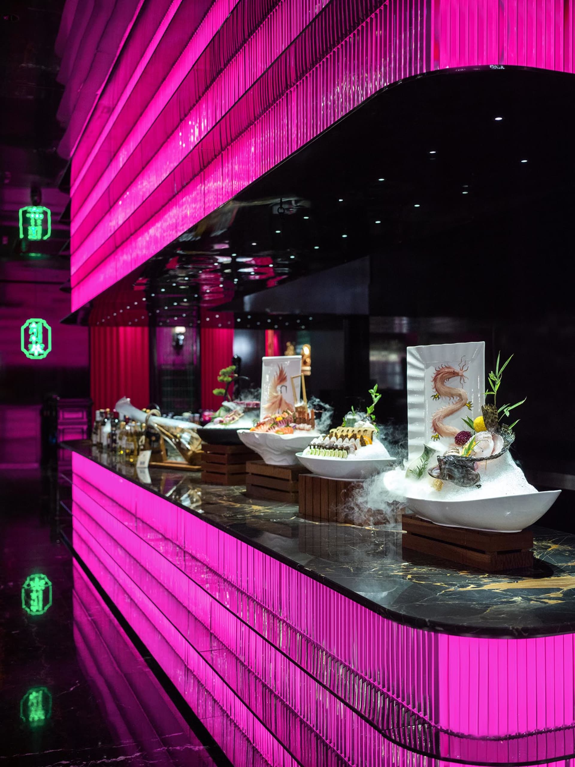 Sophisticated restaurant interior with a large dining table, pink walls, and various food items and chairs