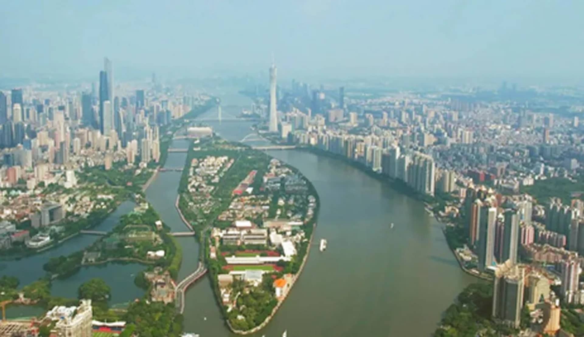 Aerial view of a bustling city with a large body of water surrounded by various buildings and boats