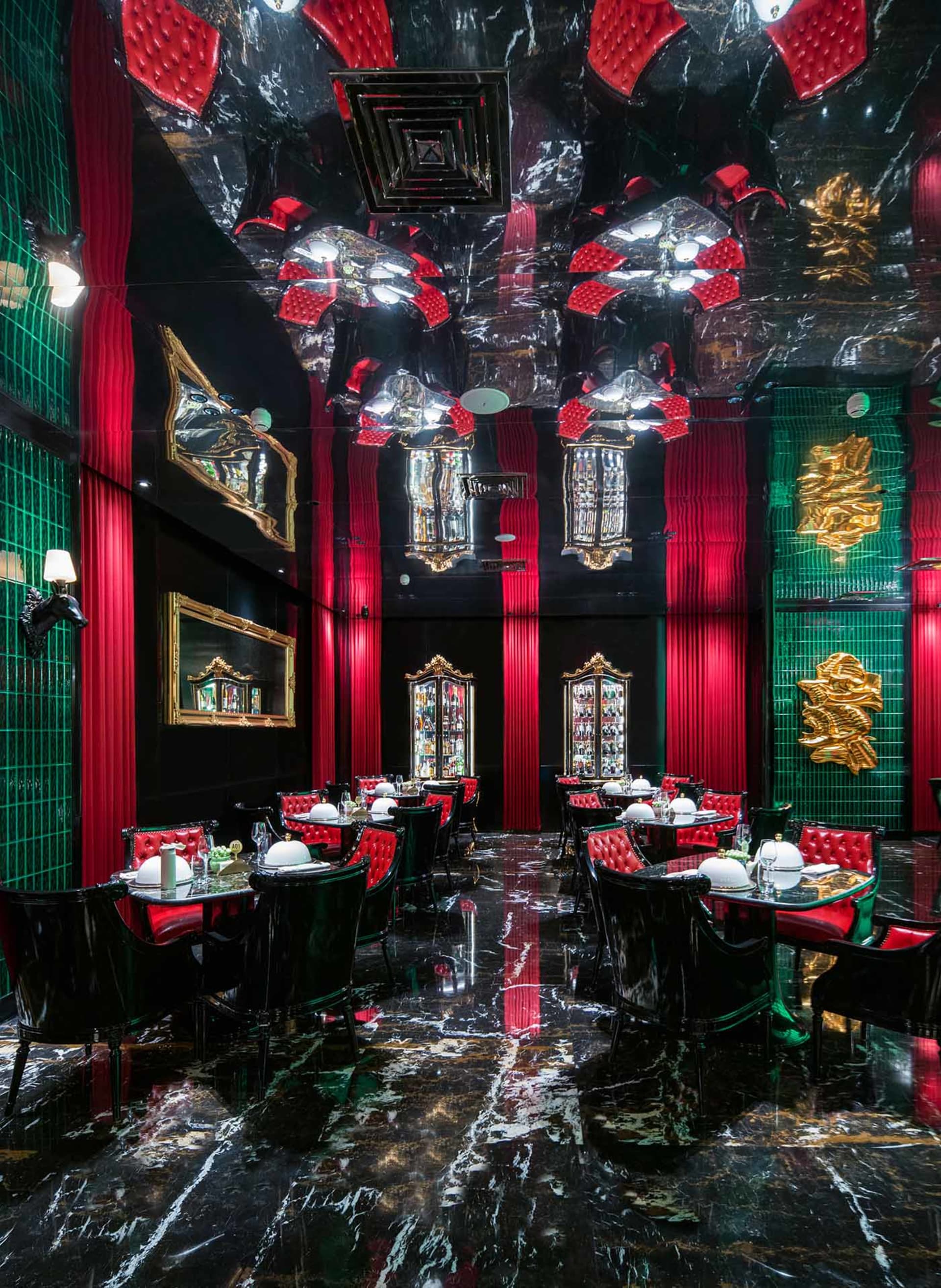 Modern restaurant interior with red walls, black accents, and tables and chairs, featuring wine glasses and a bar