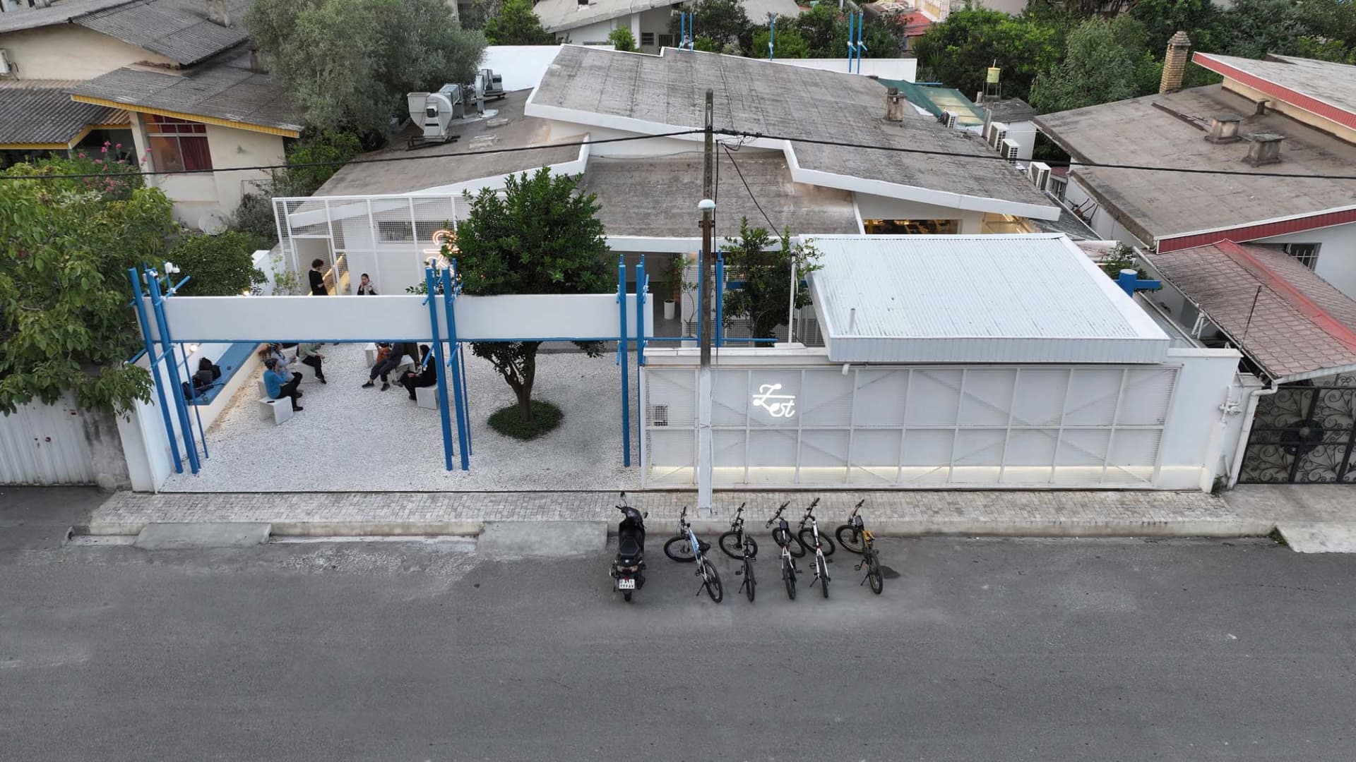 A modern and traditional building with a large white roof and a mix of concrete and wood elements, featuring a relaxed and casual outdoor space with several bicycles parked underneath