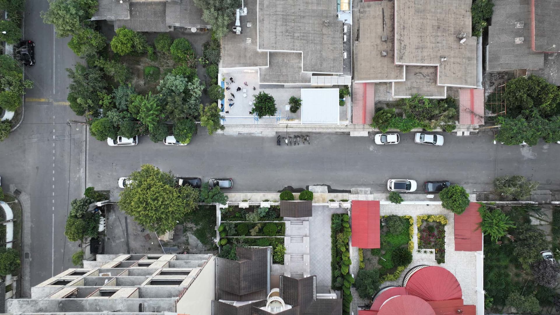 Aerial view of a residential area with brick buildings, varied architectural styles, and parked cars, evoking a sense of urban living