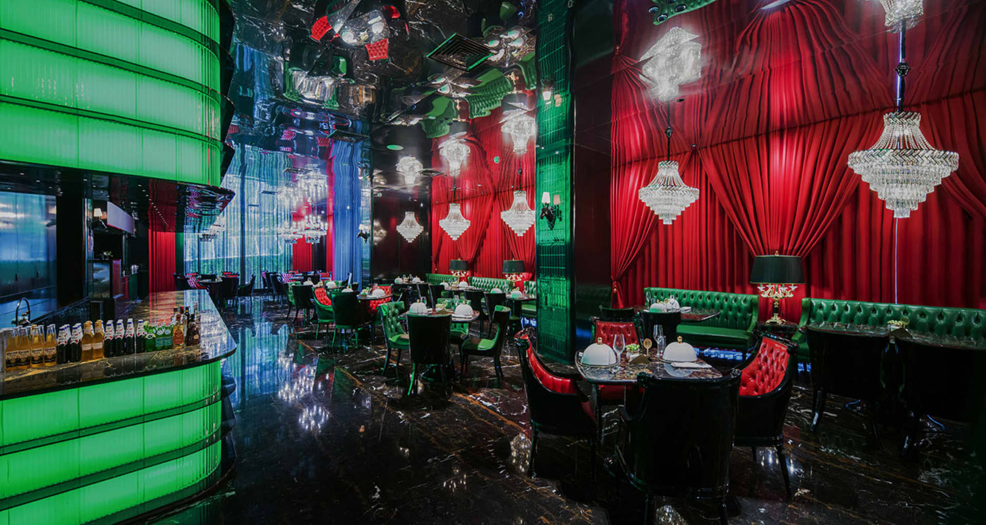 Ornate restaurant interior with red velvet walls, green accents, and cozy dining area with tables and chairs