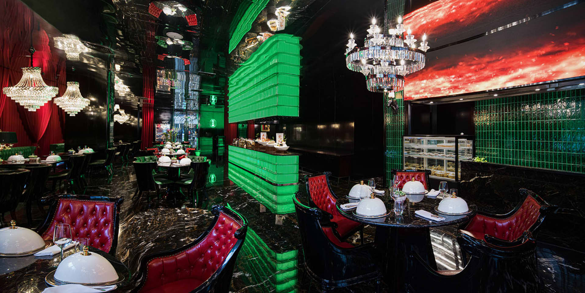 Sophisticated restaurant interior with green walls, black chairs, and tasteful decor, featuring multiple dining tables and wine glasses