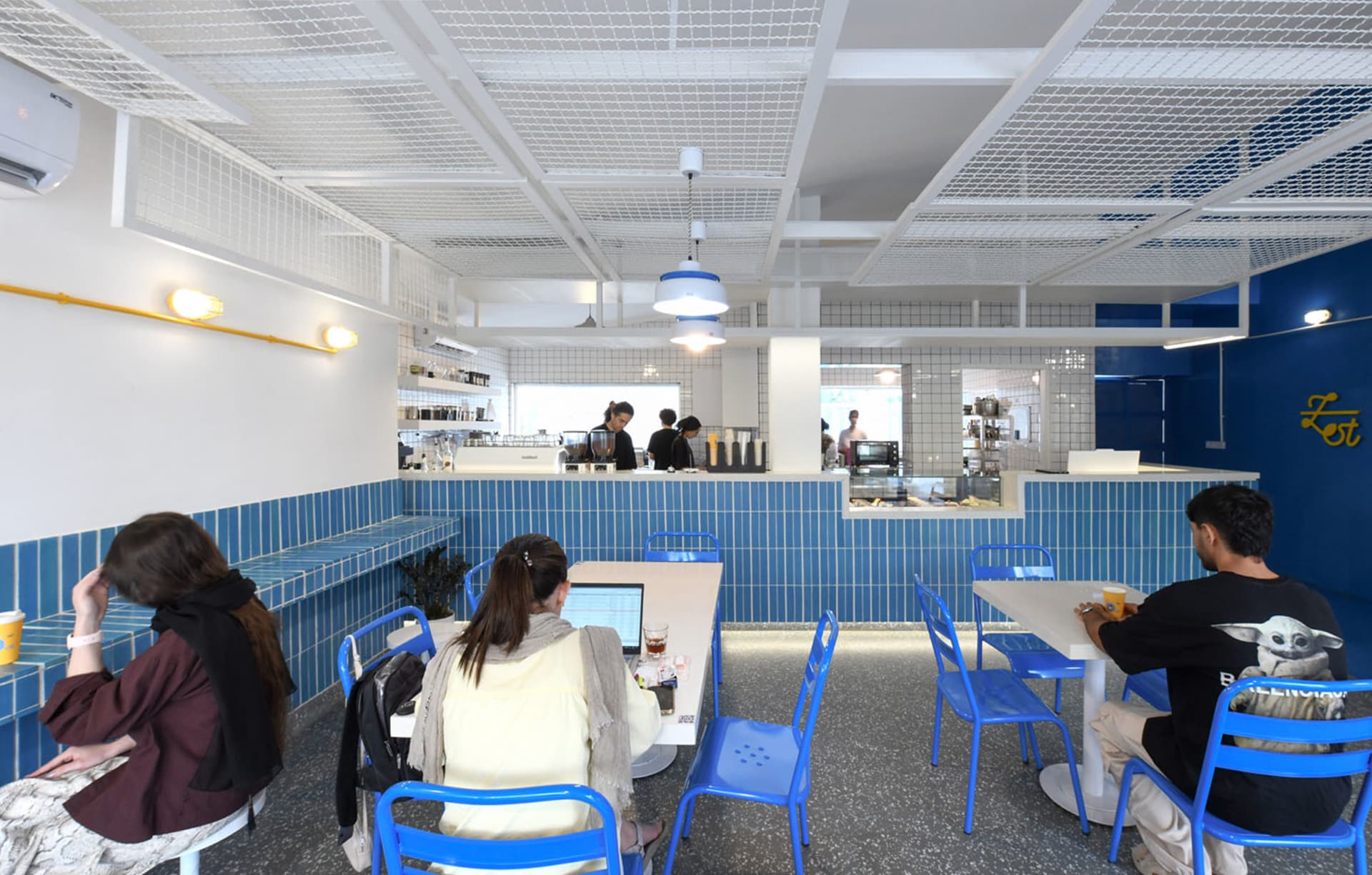 a lively restaurant interior with wooden tables and chairs, potted plants, and people dining and socializing