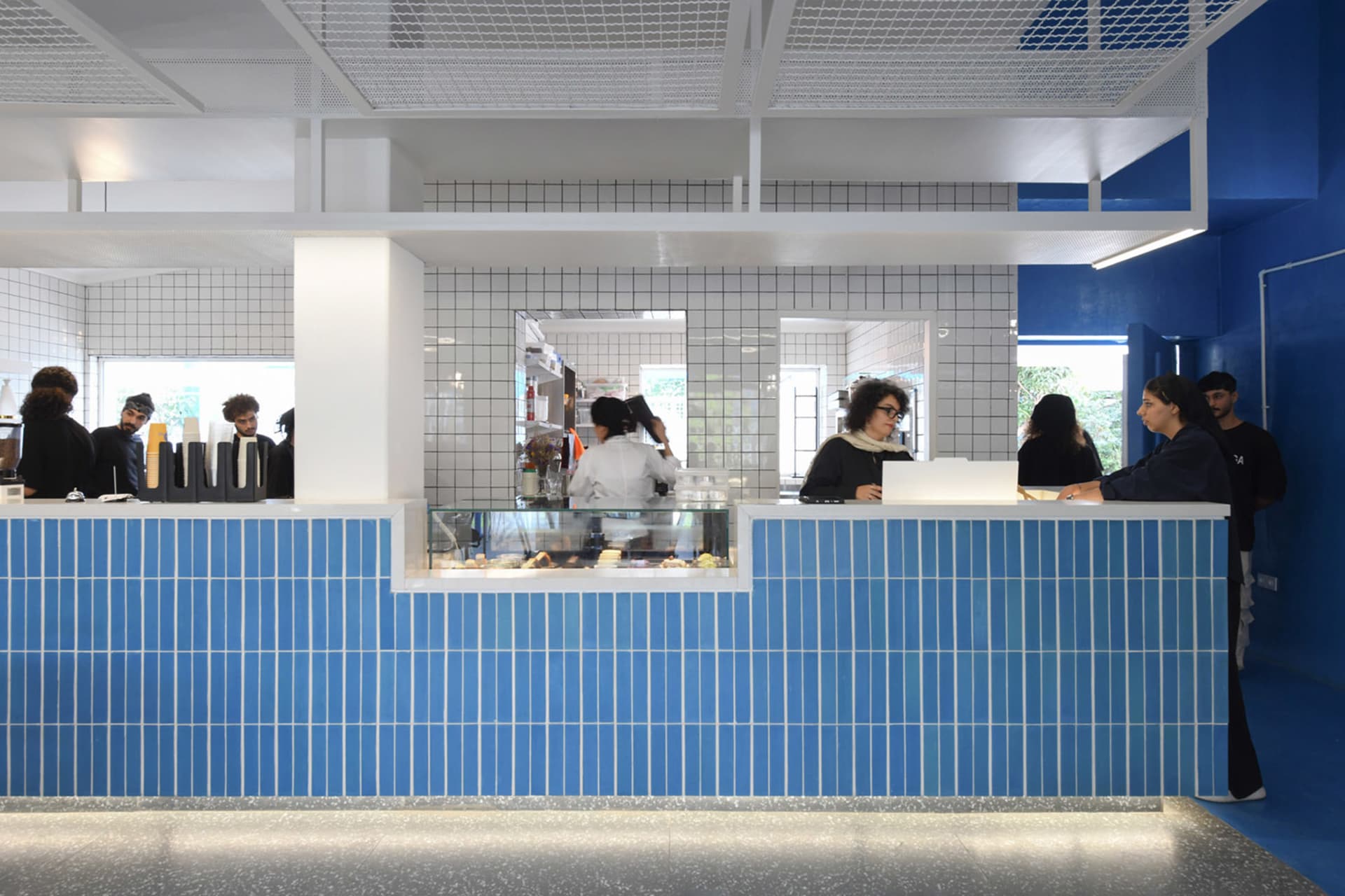 A bustling restaurant counter with people waiting in line to order food and drinks, surrounded by cups and a lively atmosphere