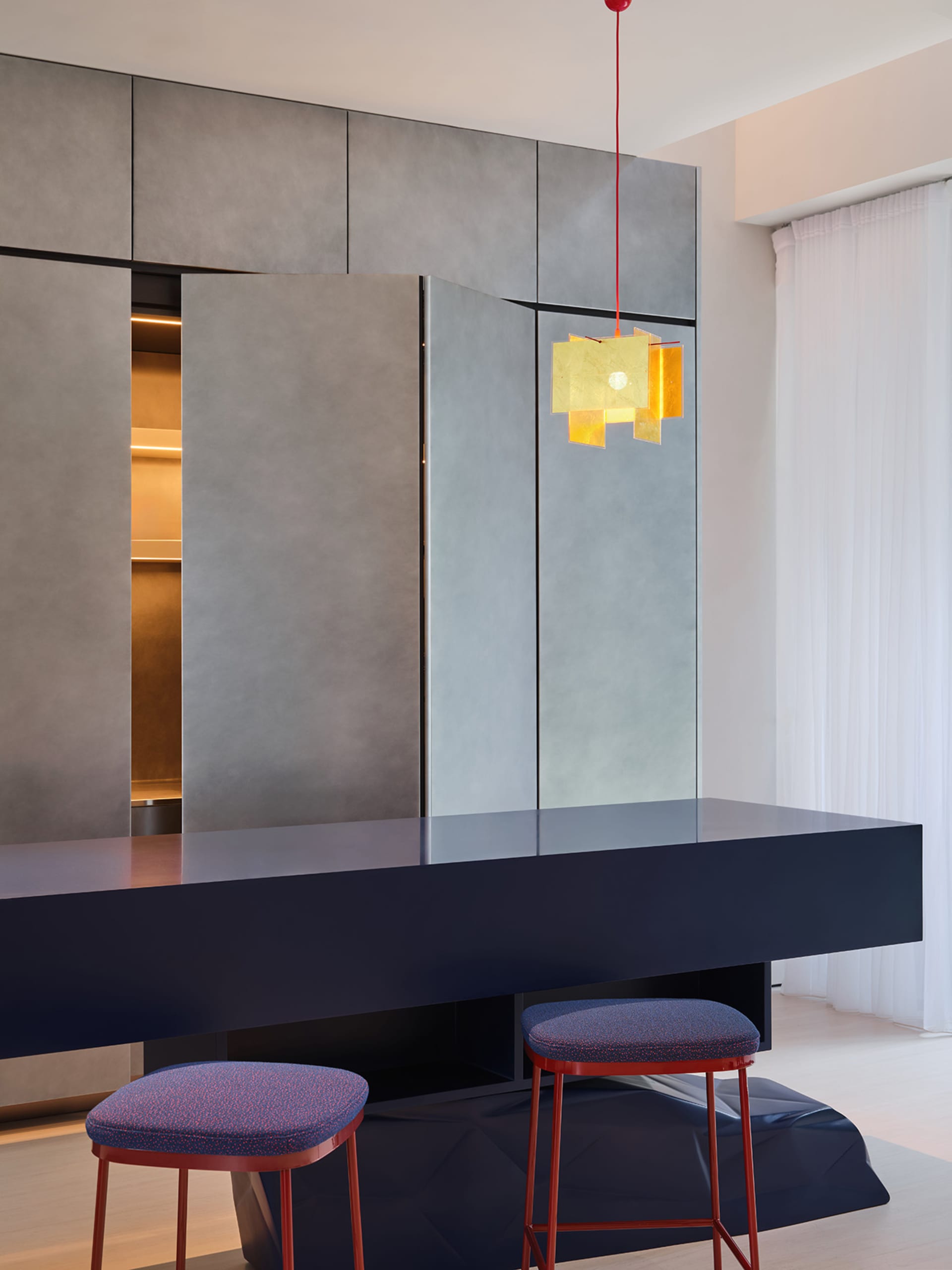 Sleek modern kitchen with grey walls and cabinets, a dining table, and two chairs, surrounded by contemporary design elements