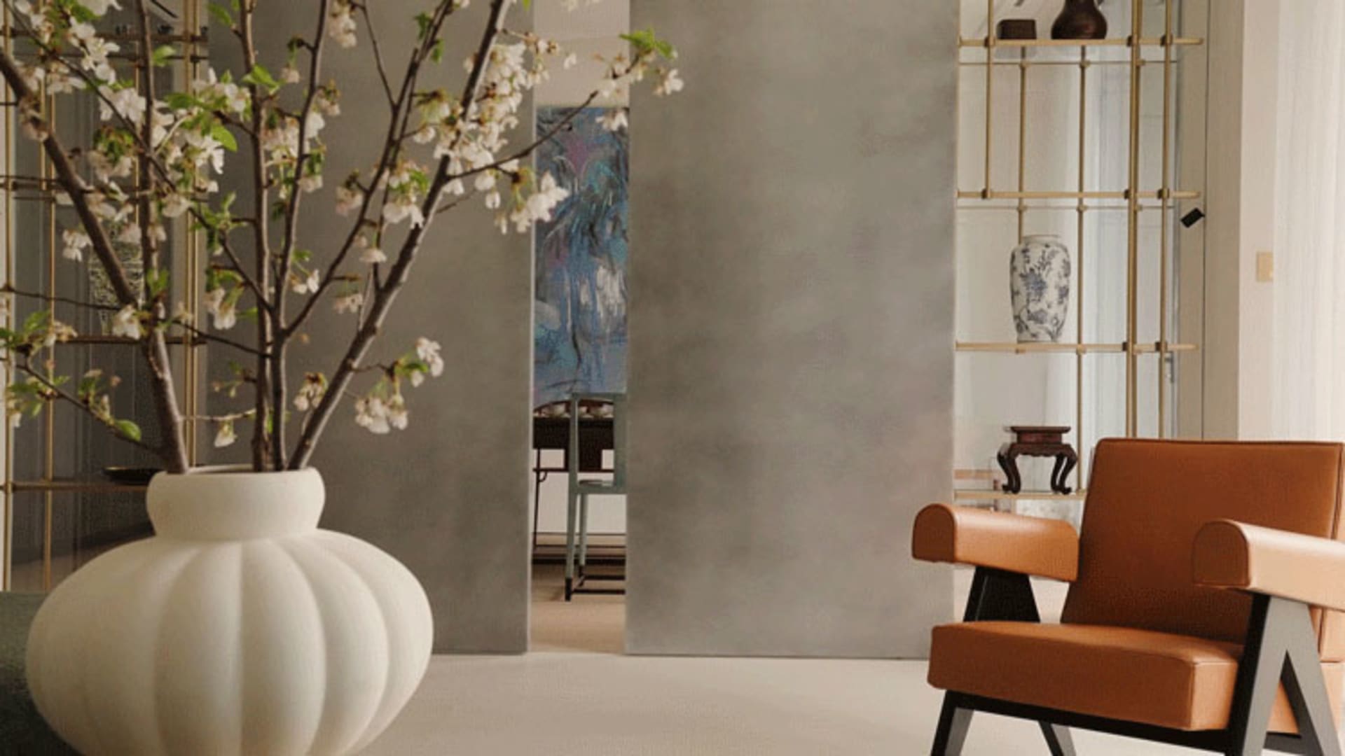 A well-lit living area with a large orange chair, vases, and a potted plant, creating a comfortable atmosphere