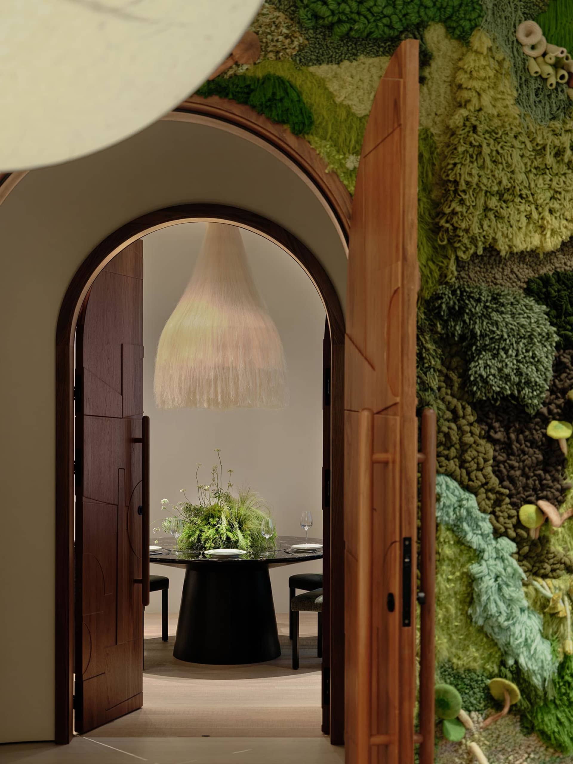 Cozy dining space with a black table, chairs, and a potted plant, set up for a meal or gathering