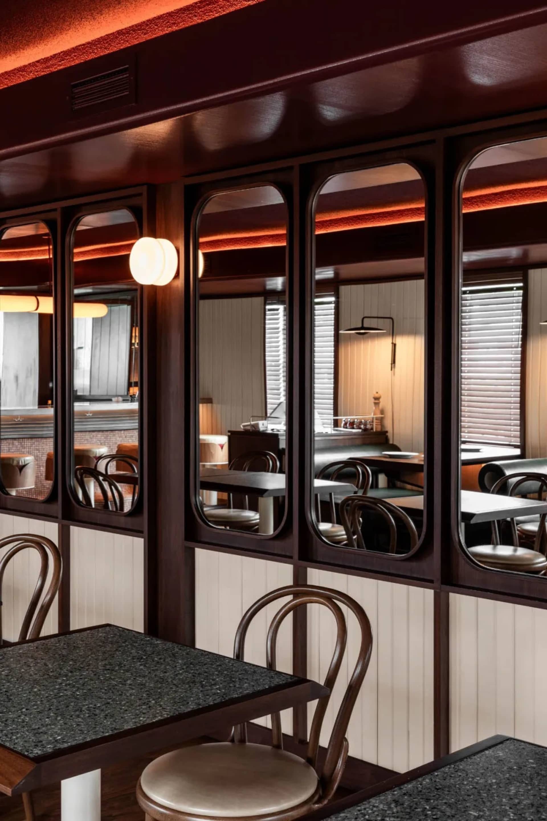 A well-lit restaurant interior with wooden walls and tables, featuring chairs and a cozy atmosphere